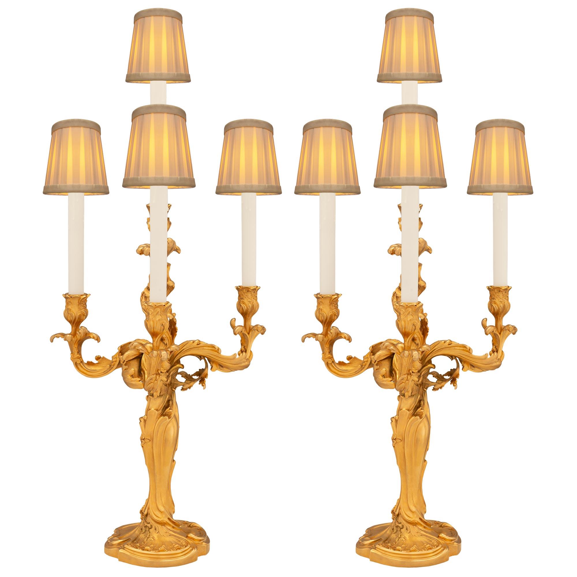 Une belle et grande paire de candélabres en bronze doré Louis XV de la fin du 19ème siècle, signée E. Lelivevre et coulée par la Fonderie Susse Frères. La paire de candélabres électrifiés à quatre bras repose sur des bases circulaires avec des