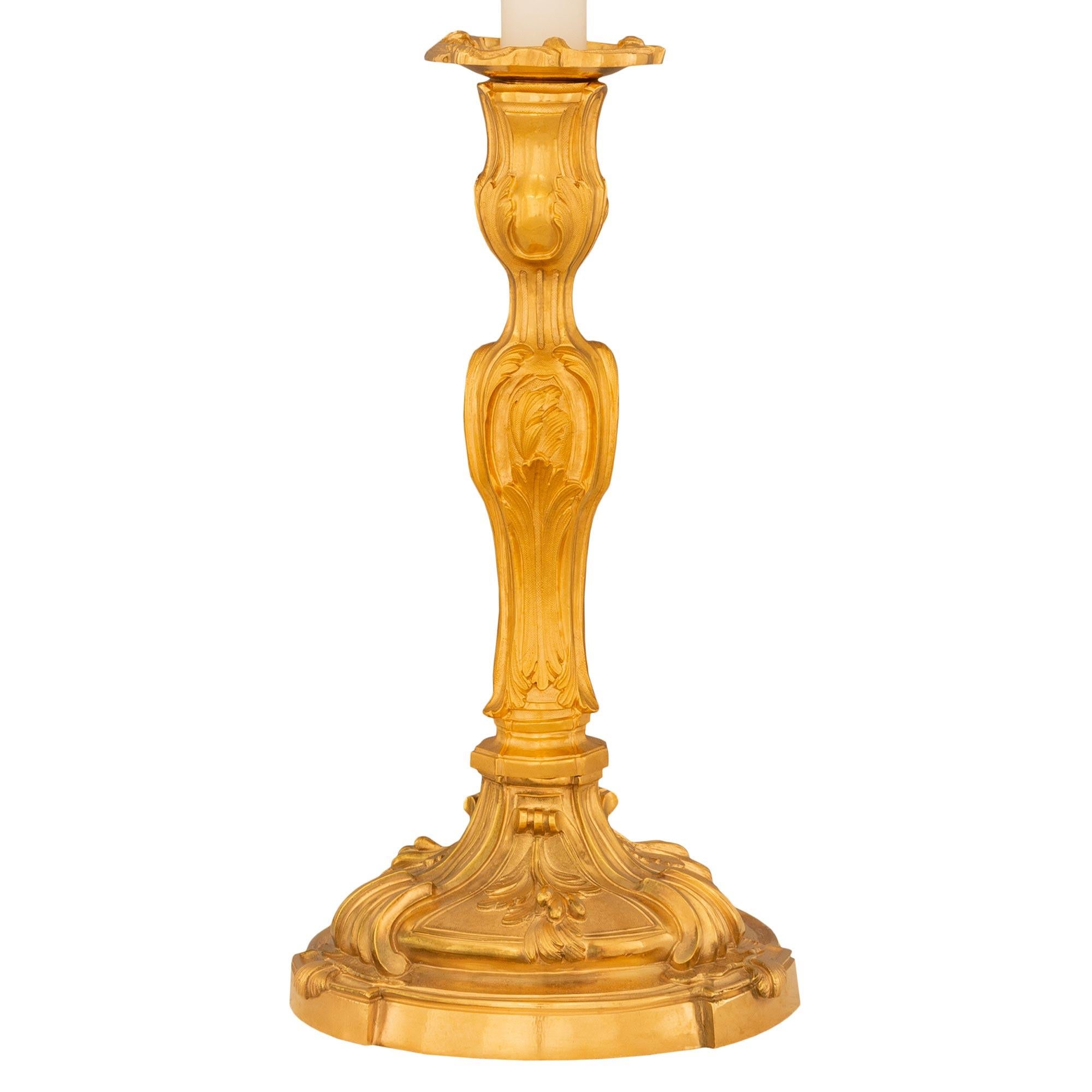 Ravissante paire de lampes-bougies en bronze doré de style Louis XV du XIXe siècle. Chaque lampe est surmontée d'une base circulaire avec trois supports en saillie décorés de feuilles d'acanthe enroulées. Le support central présente d'autres