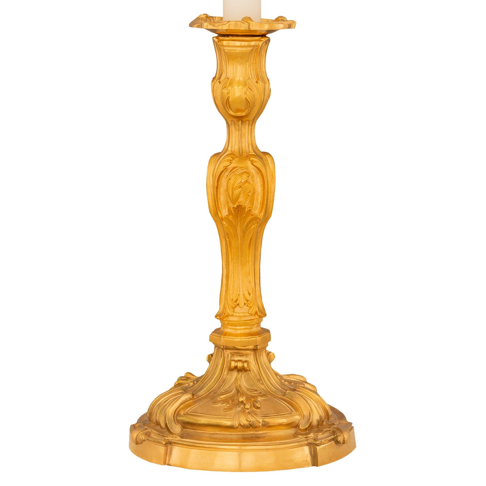 Una bella coppia di lampade a candelabro francesi del XIX secolo in stile Luigi XV. Ogni lampada è sollevata da una base circolare con tre sottili sostegni sporgenti decorati da foglie d'acanto a volute. Il supporto centrale presenta ulteriori
