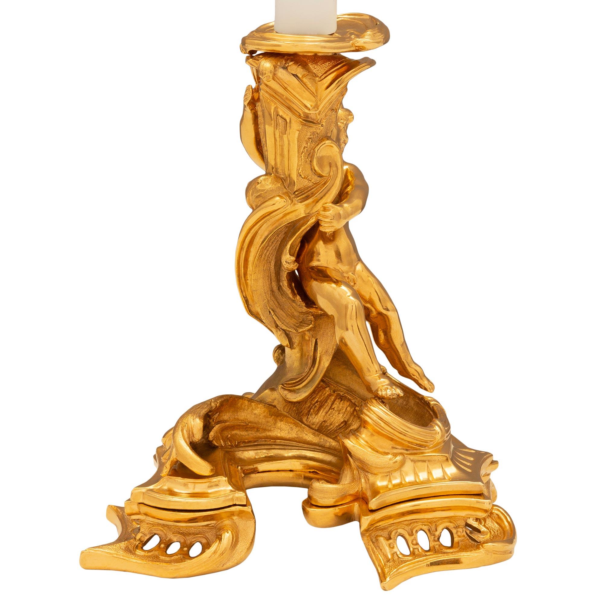 Une étonnante et impressionnante paire de lampes-bougies en bronze doré de style Louis XV du XIXe siècle. Chaque lampe est soutenue par une base à trois côtés avec des motifs de volutes de Rocaille percés. Le corps de chaque lampe représente un