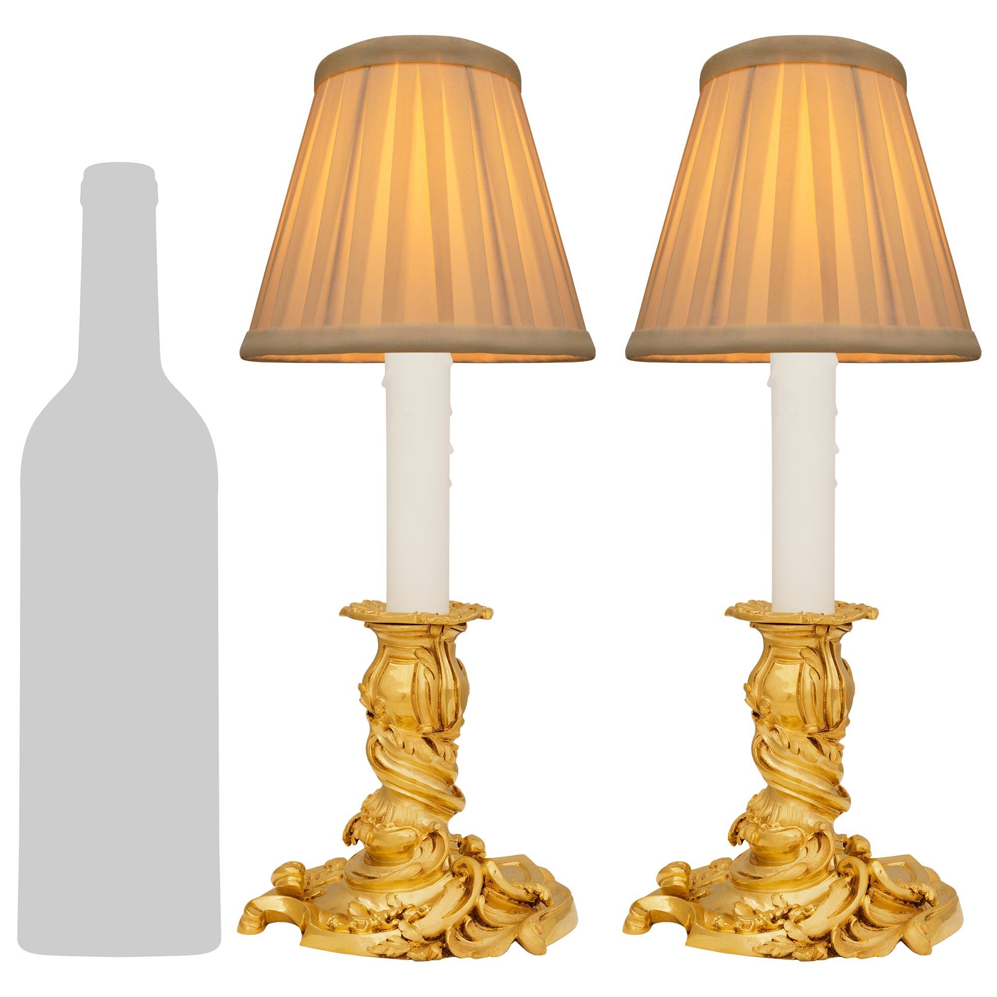 Un par de lámparas candelabro de Ormolu de alta calidad y gran elegancia, francesas del siglo XIX, estilo Luis XV. Este encantador par de lámparas se eleva sobre una base asimétrica con un intrincado diseño Rocaille de elementos foliados en espiral.