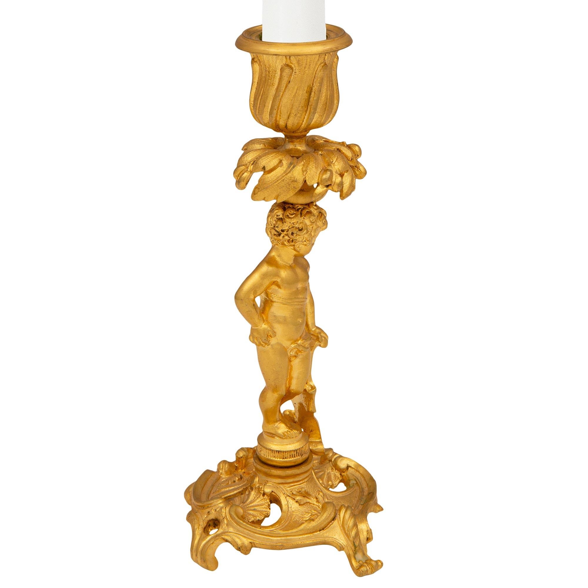 Ein exquisites, echtes Paar französischer Kerzenleuchter aus dem 19. Jahrhundert im Stil Louis XV. aus Ormolu. Jeder Kerzenhalter steht auf einem eleganten, durchbrochenen Rundsockel mit vier verschnörkelten Akanthusblattstützen. In der Mitte stehen