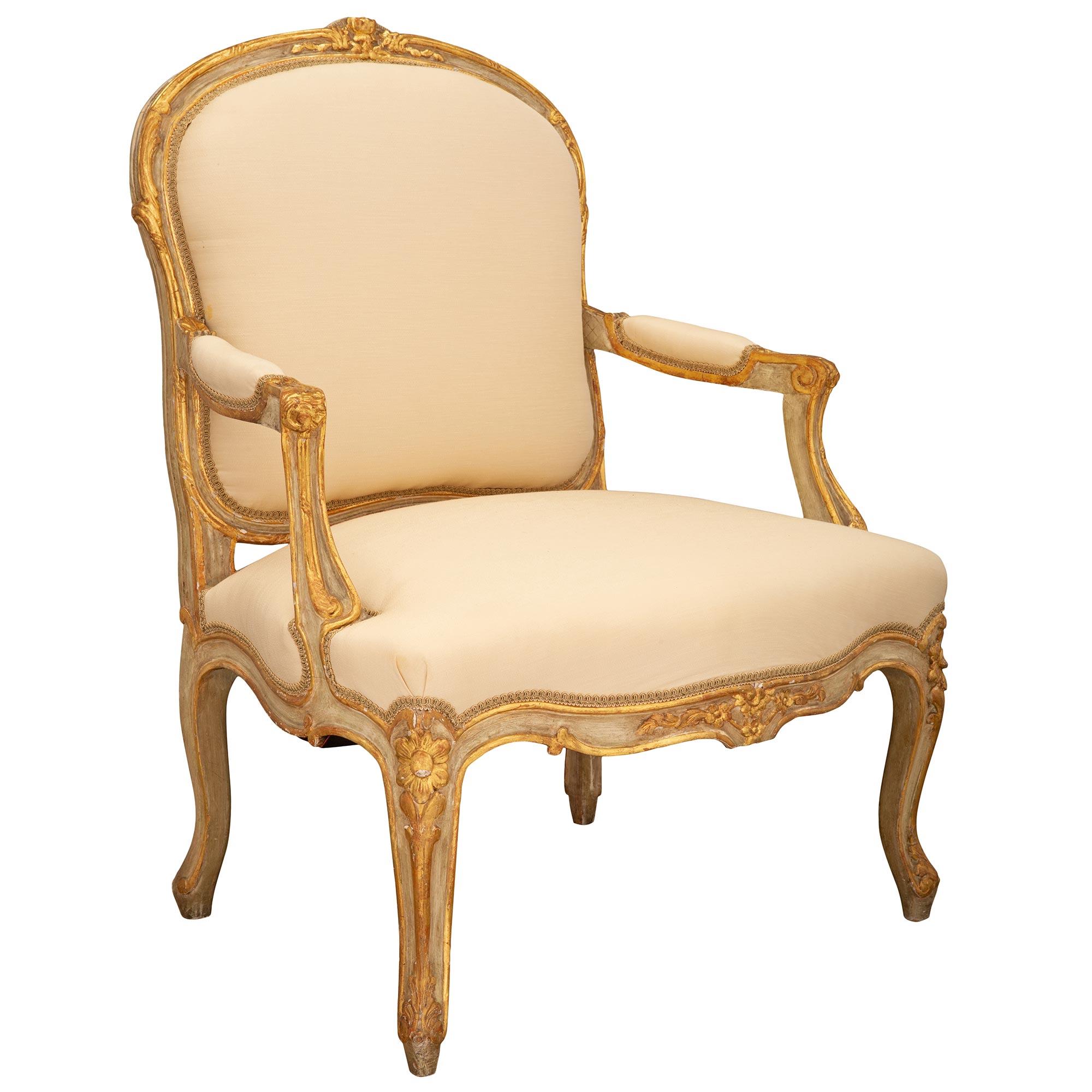 A most elegant pair of French 19th century Louis XV st. patinated and giltwood armchairs. Each armchair is raised by slender cabriole legs with beautiful scrolled giltwood acanthus leaves and charming richly carved corner rosettes set on patinated