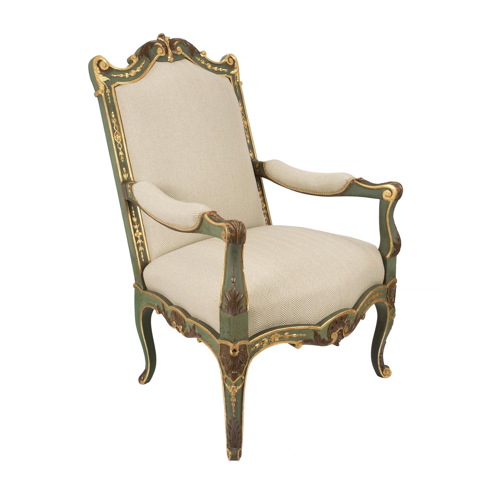 A pair of country French early 19th century Louis XV st. patinated and giltwood armchairs from Provence. Each armchair is raised by elegant cabriole legs with scrolled feet and brown polychrome acanthus leaves and finely carved seashell cabochons at
