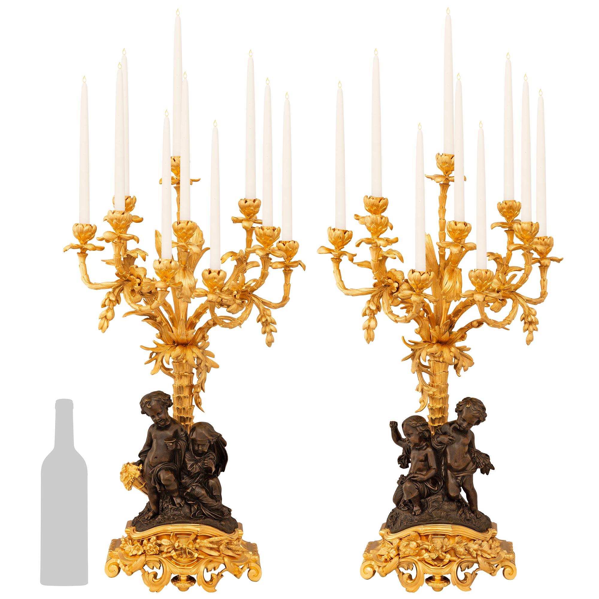 Un'impressionante coppia di candelabri francesi del XIX secolo in bronzo patinato e Ormolu. Ogni candelabro a nove bracci è sollevato su un piedistallo a gradini in Ormolu traforato dalla forma unica, con disegni di fogliame a scorrimento,