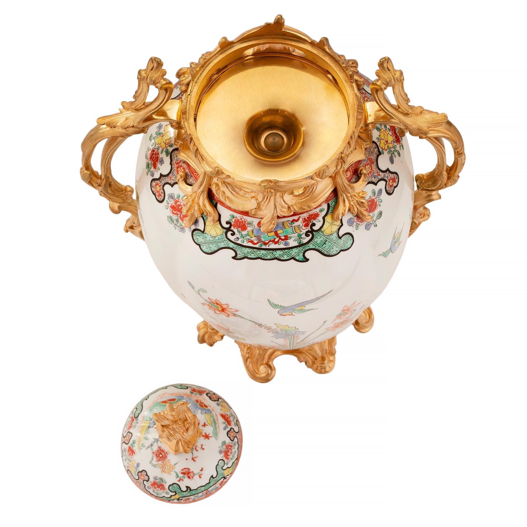 A sensational and large scaled pair of French 19th century Louis XV st. Samson porcelain and ormolu mounted lidded urns. The pair are raised by a scalloped ormolu base with designs of acanthus leaves. The circular oblong vase above has most elegant