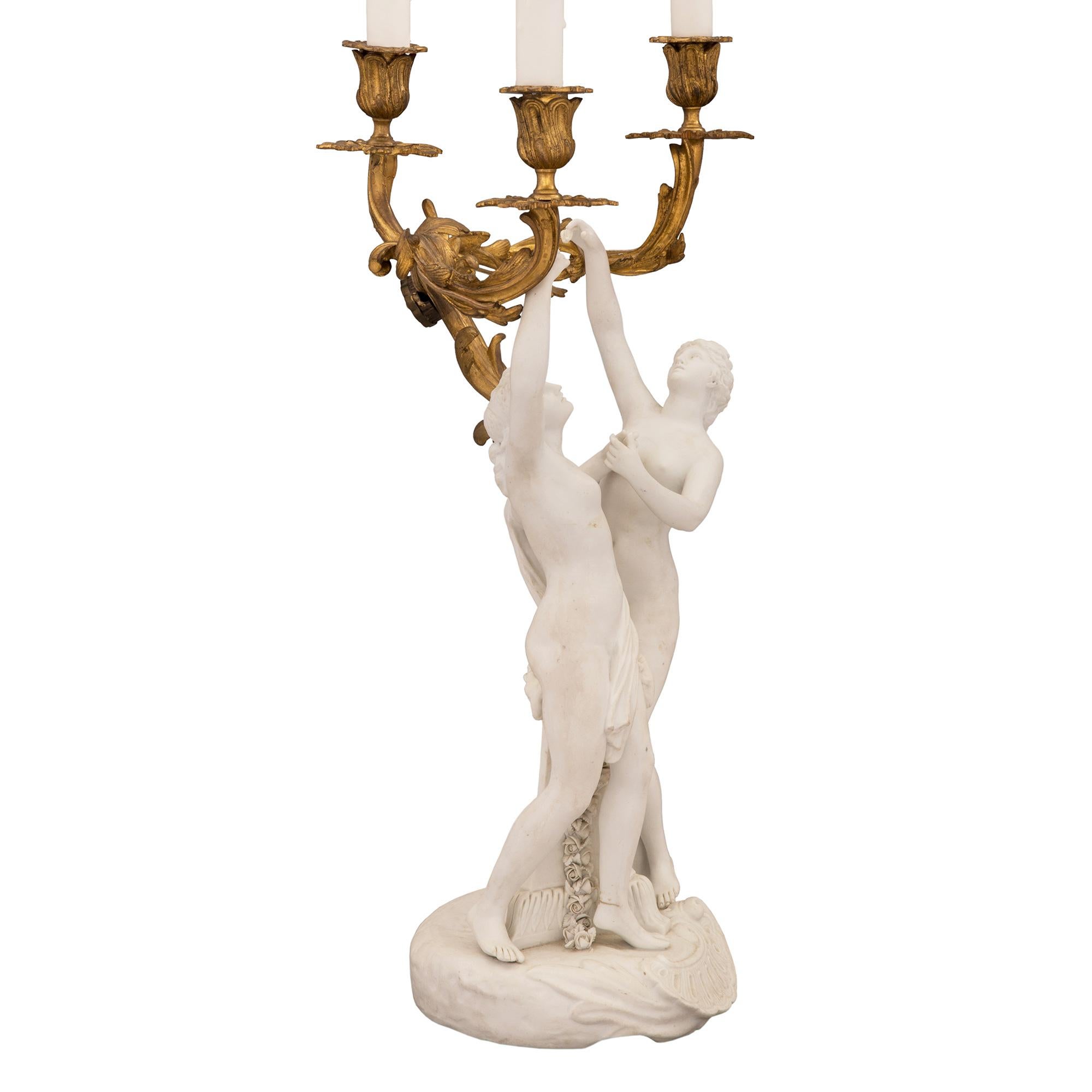 An elegant pair of French 19th century Louis XV st. ormolu and porcelain electrified candelabras lamps, signed Sèvres. Each beautiful lamp is raised by a circular Biscuit de Sèvres porcelain base with large 'C' scrolled reserves and ground like