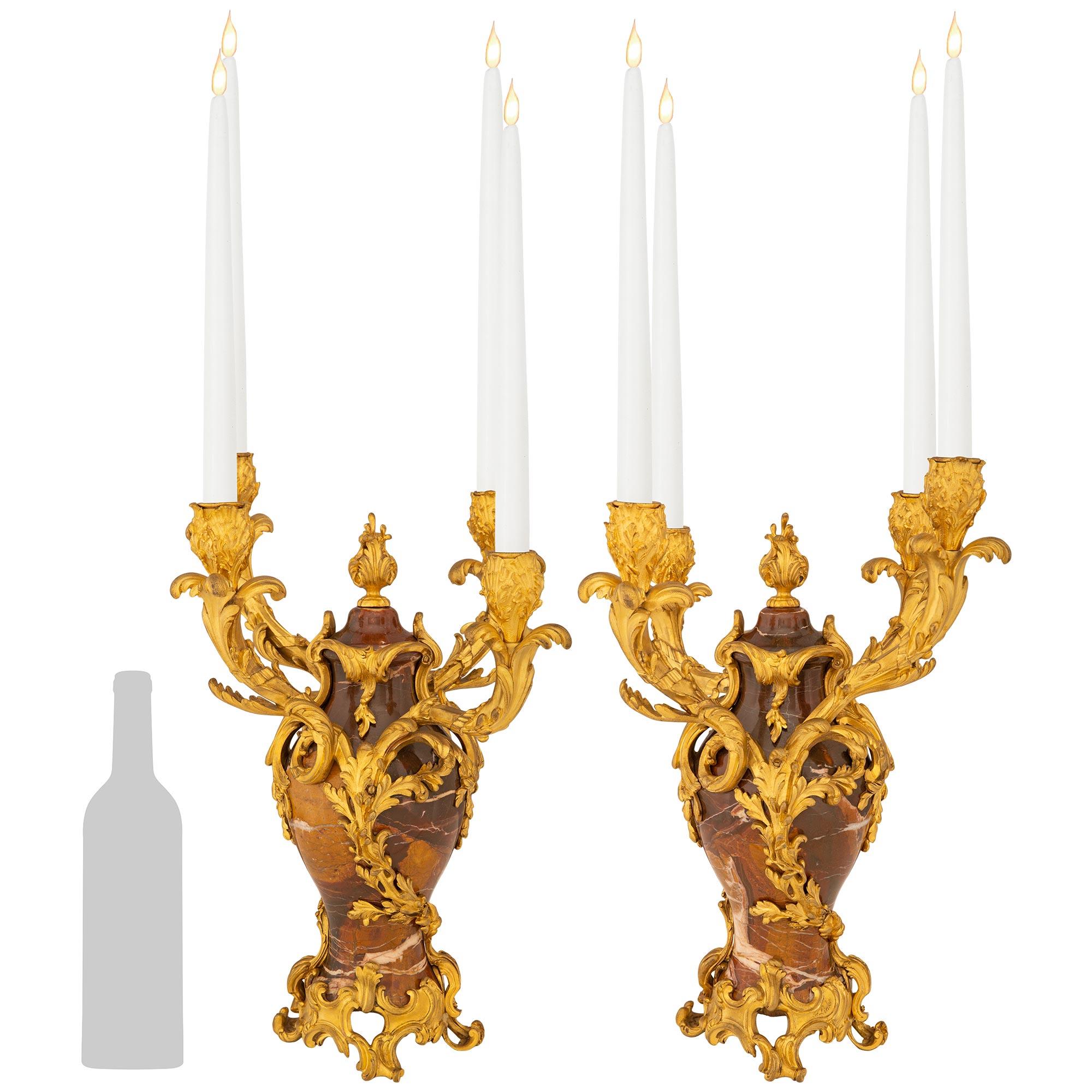 Una magnifica coppia di candelabri francesi del XIX secolo in stile Luigi XV in Ormolu e marmo Breche Rouge, firmati F. Linke. Ogni candelabro a quattro bracci si erge su una base in Ormolu a volute traforate con impressionanti disegni foliati in
