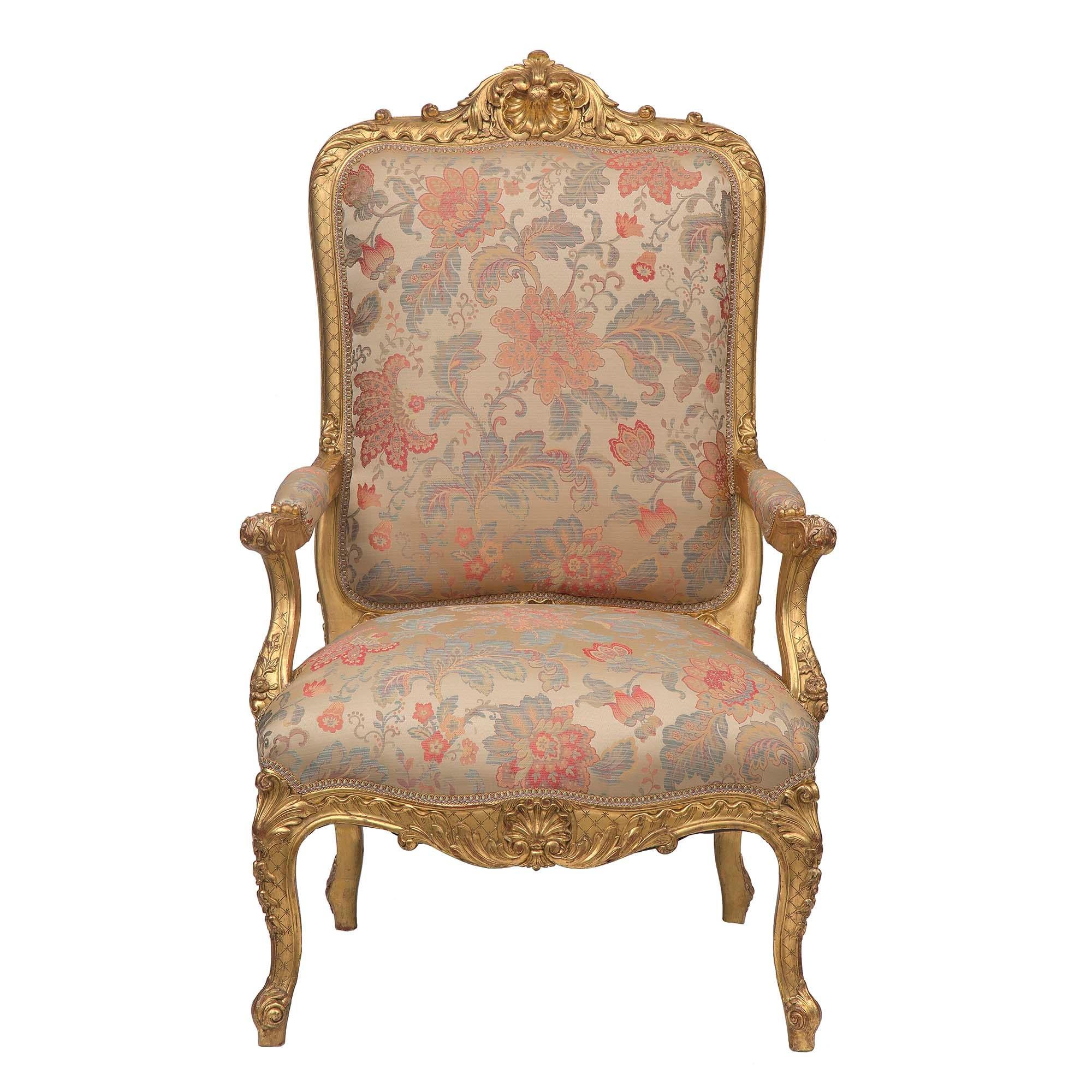 Una sensazionale coppia di poltrone con schienale alto in legno dorato Luigi XV del XIX secolo. Ciascuna di esse è sollevata da belle gambe cabriole riccamente intagliate con un elegante sfondo a reticolo e grandi foglie d'acanto e rosette. Il