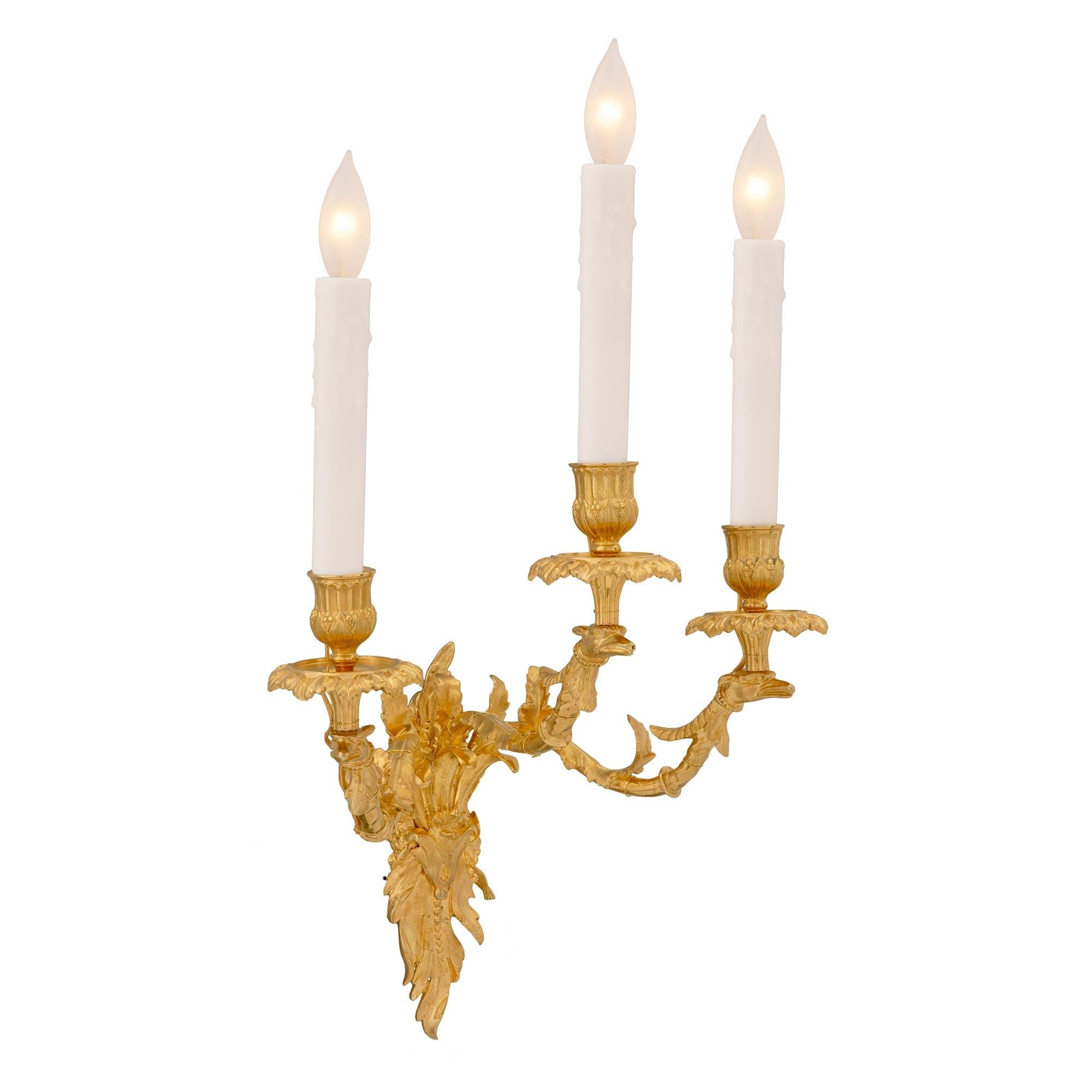 Une belle paire d'appliques à trois bras de lumière en bronze doré de style Louis XV du 19ème siècle. Chaque applique est ornée d'une plaque arrière richement ciselée et feuillagée avec de fines feuilles d'acanthe. Les bras à volutes élégantes