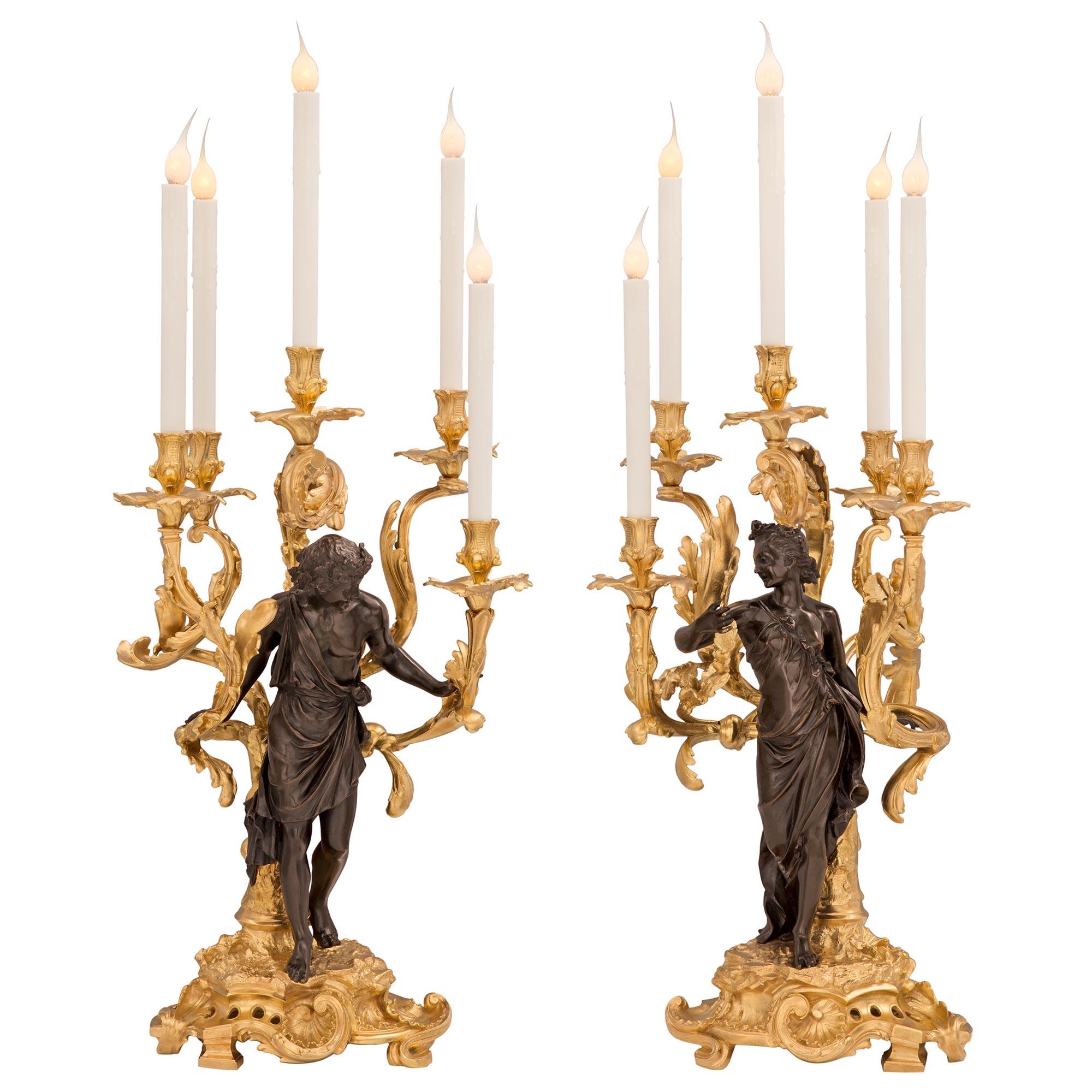 A stunning and extremely high quality true pair of French 19th century Louis XV st. patinated bronze and ormolu lamps. Each five arm candelabra lamp is raised by a sensational pierced Rocaille ground like designed base with a beautiful scrolled
