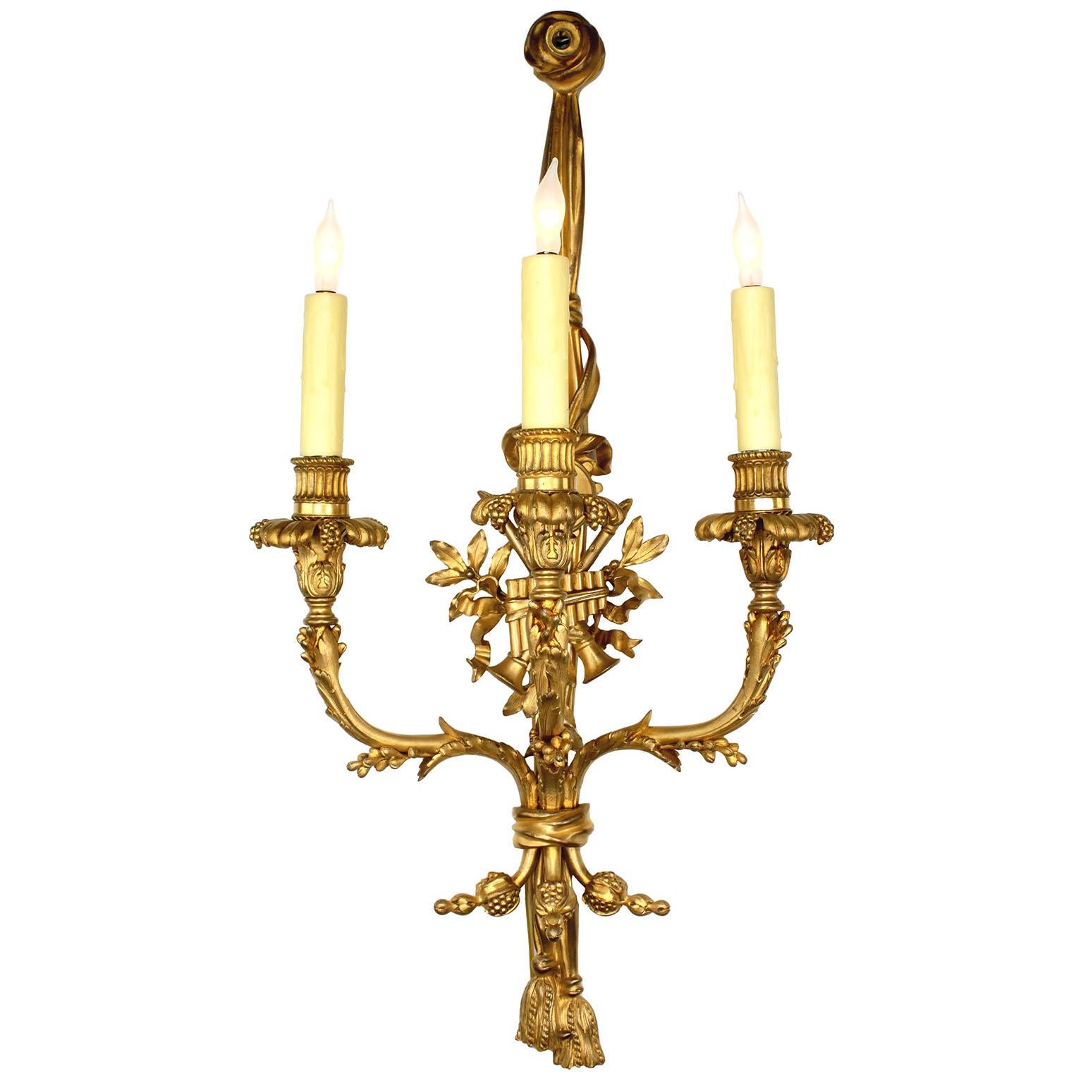 A very fine pair of French 19th Century Louis XV style three-light gilt-bronze wall lights (Sconces), attributed to Henri Dasson (1825–1896). The elongated ormolu tassel body surmounted with a ribbon-tied allegorical shield with musical instruments