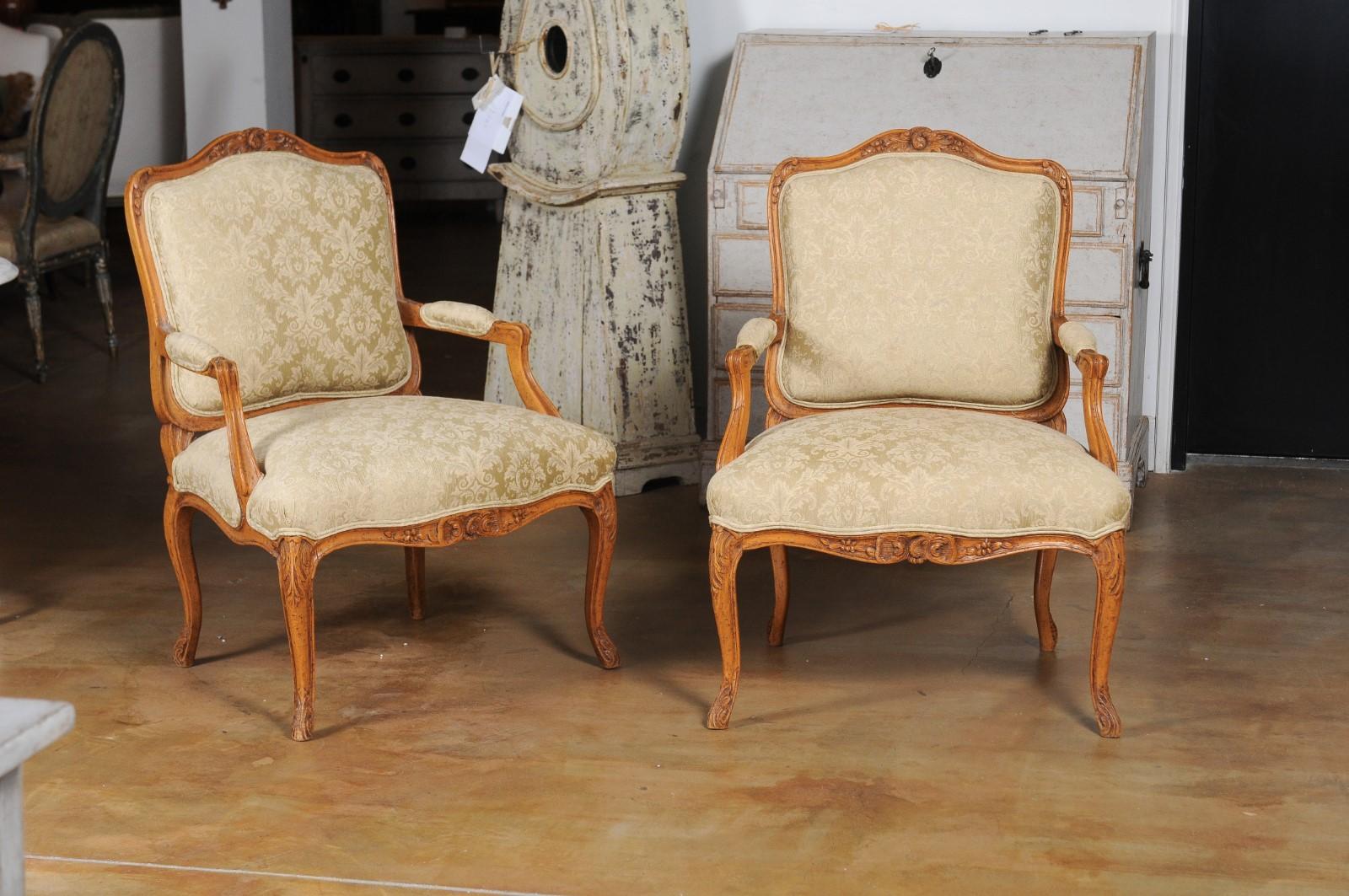 A pair of French Louis XV style in light walnut fauteuils from the 19th century, with new upholstery. Created in France during the 19th century, this pair of armchairs presents the stylistic characteristics of the Louis XV era. Each chair features a