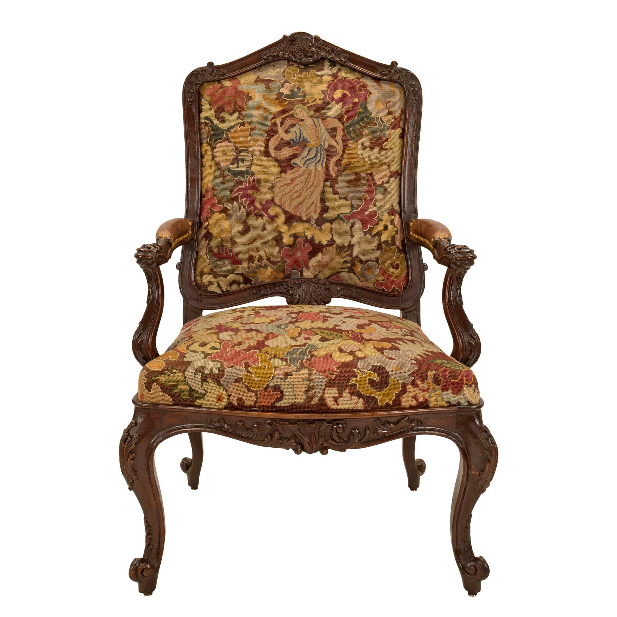 A beautiful pair of French 19th century Louis XV st. walnut and tapestry À Chasis armchairs. Each arm chair is raised by elegant cabriole legs with scrolled feet and richly carved foliate designs. The arbalest shaped frieze displays central foliate