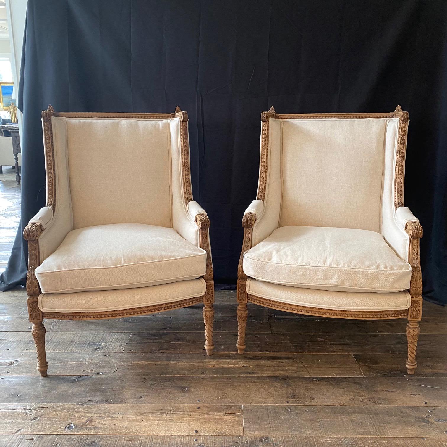 Elegant antique pair of French Louis XV style walnut wingback bergères from the 19th century, with completely carved frame décor, new neutral high end upholstery and Louis XV classic features. Each chair features a wingback, designed to give more