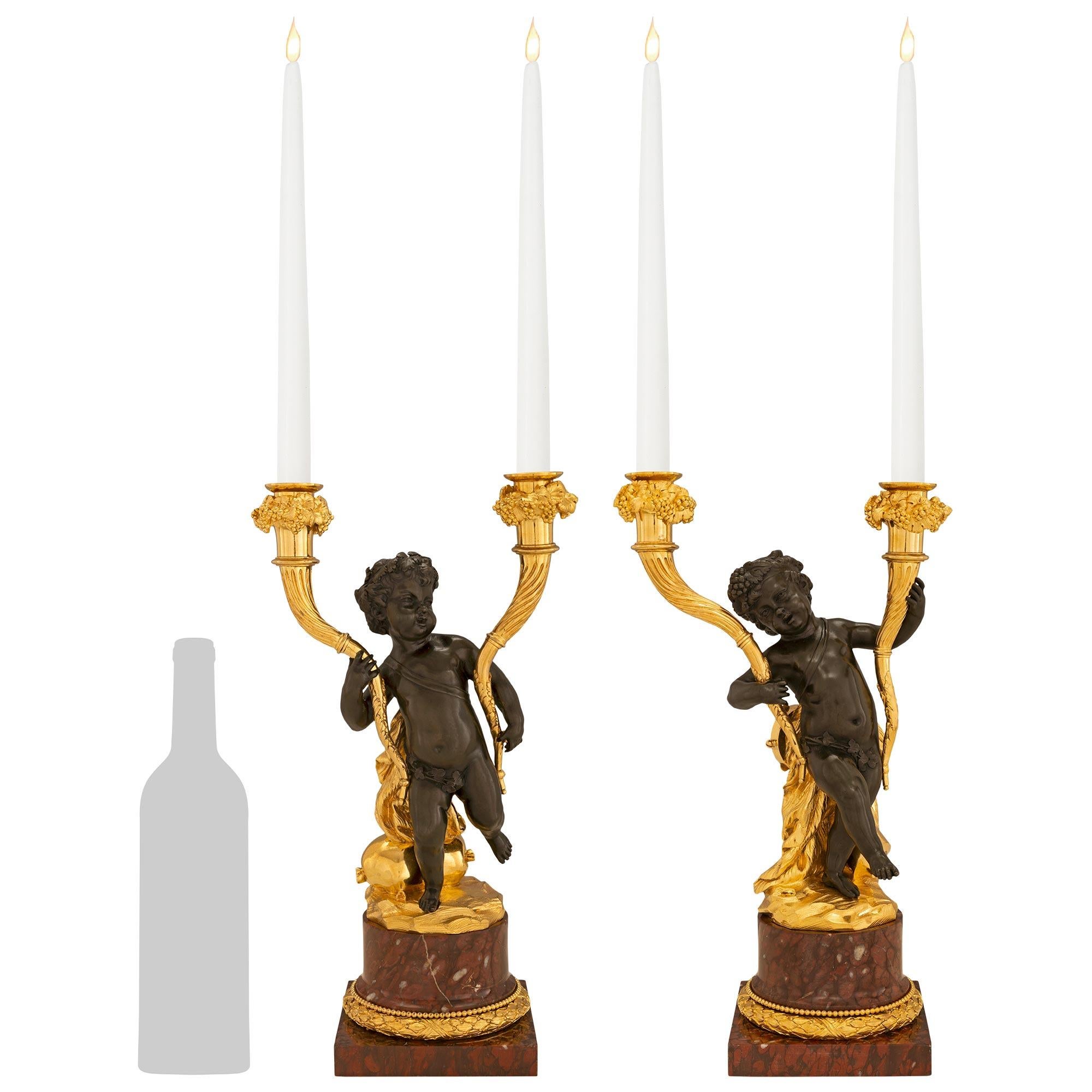 A very high quality and elegant pair of French 19th century Louis XVI st. Patinated Bronze, Ormolu and Rouge Griotte marble two arm candelabras. Each candelabra is raised by a square Rouge Griotte marble plinth below a richly chased berried laurel