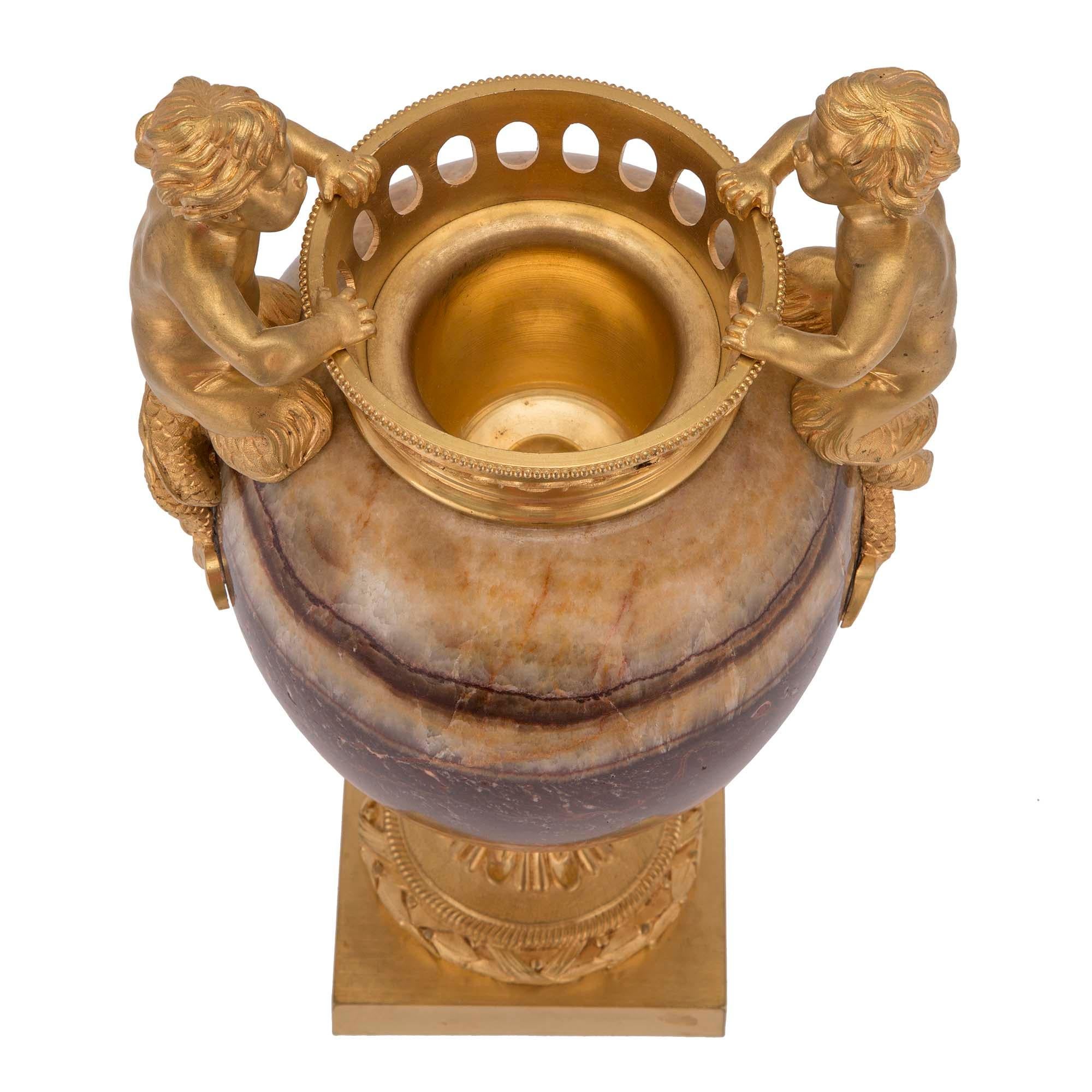 A truly stunning pair of French 19th century Louis XVI st. Agate and ormolu urns. Each is raised on a square ormolu base with laurel wreath and fluted socle with large foliate. The beautiful and impressive richly hued agate body is decorated with