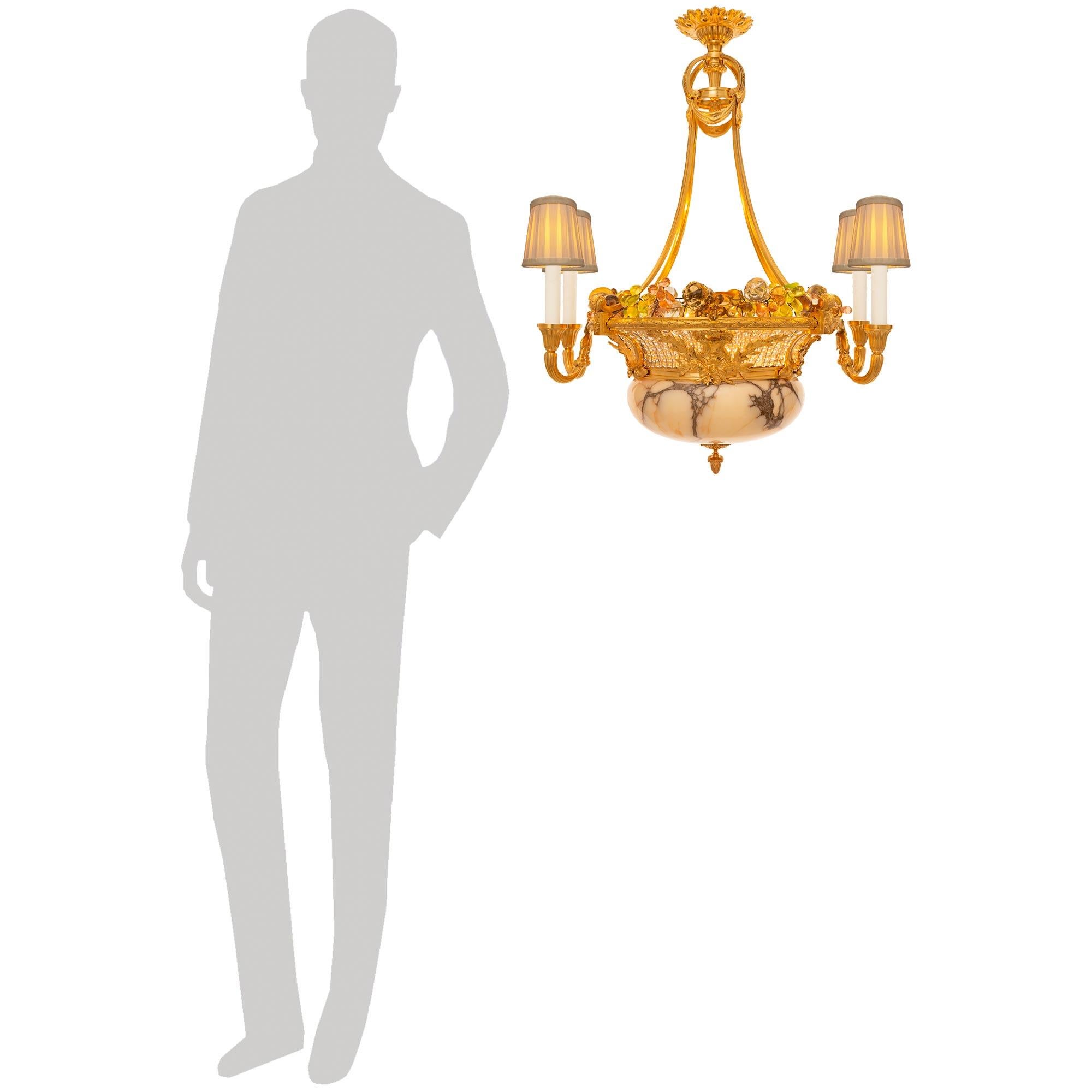 Una coppia unica e molto elegante di lampadari francesi del XIX secolo in stile Luigi XVI in alabastro, ormolu e vetro. Ogni attraente lampadario a cinque luci è centrato da una ghiera in Ormolu situata al centro della base del corpo in Alabastro a