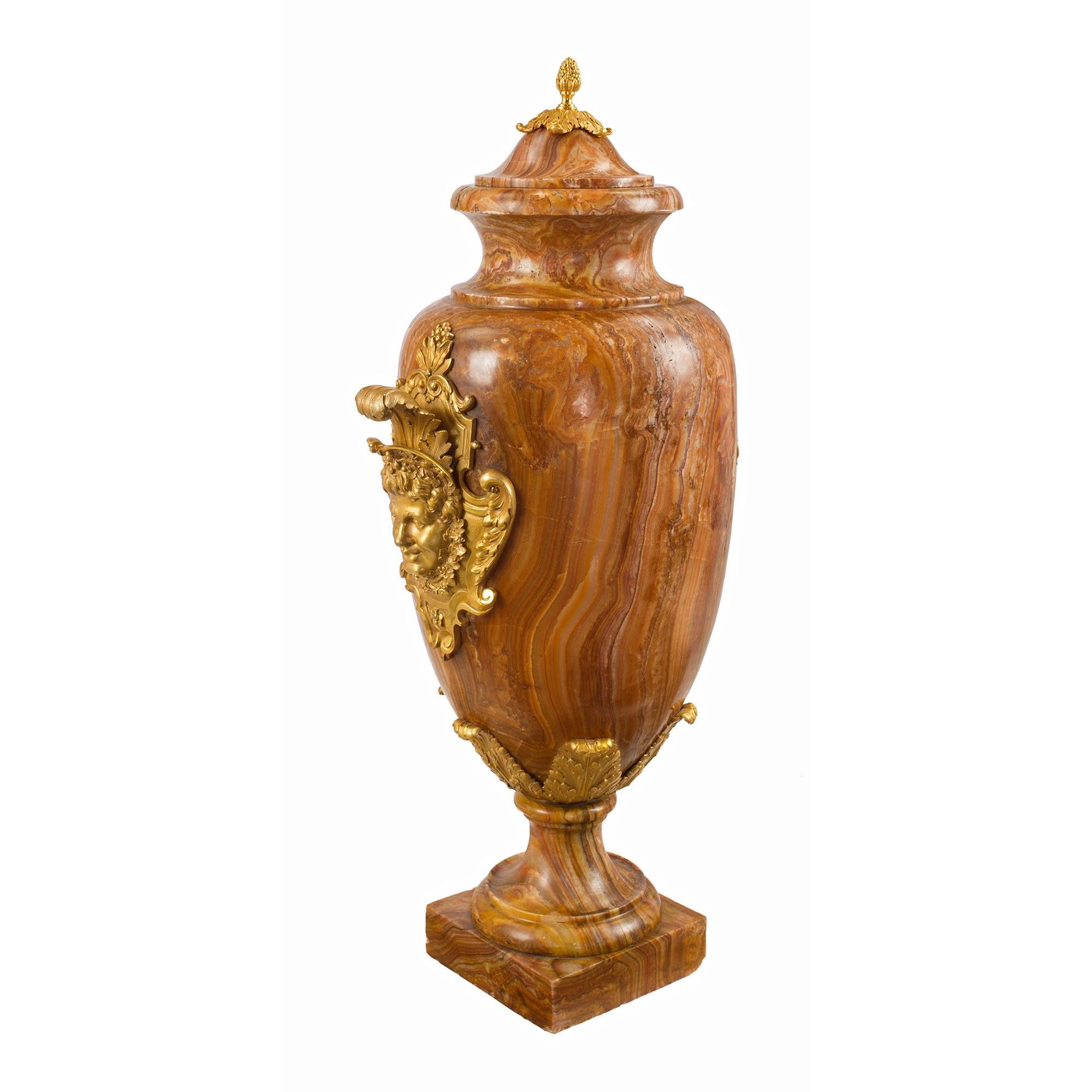 A striking and large scale pair of French 19th century Louis XVI st. Alabastro Fiorito and ormolu lidded urns. Each urn is raised by a square base below the circular mottled socle pedestal. The elegantly shaped body displays finely detailed ormolu