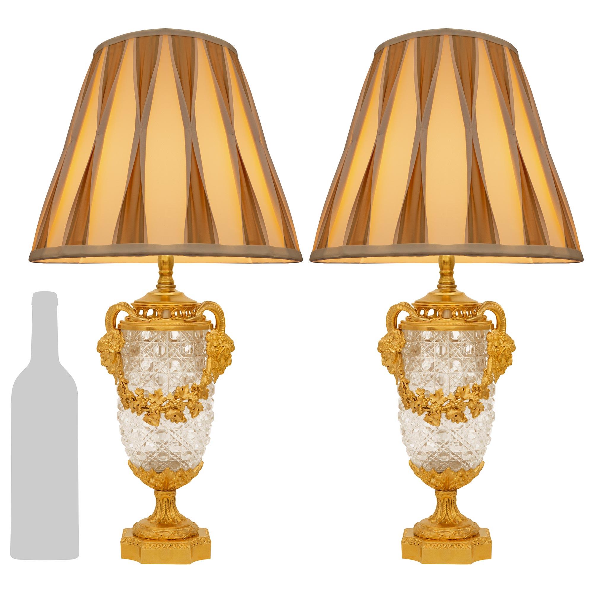 Une spectaculaire et très élégante paire de lampes en cristal et bronze doré de Baccarat du XIXe siècle. Chaque lampe en cristal est surmontée d'une base carrée en bronze doré tacheté avec des coins coupés sous une couronne de feuillage et des