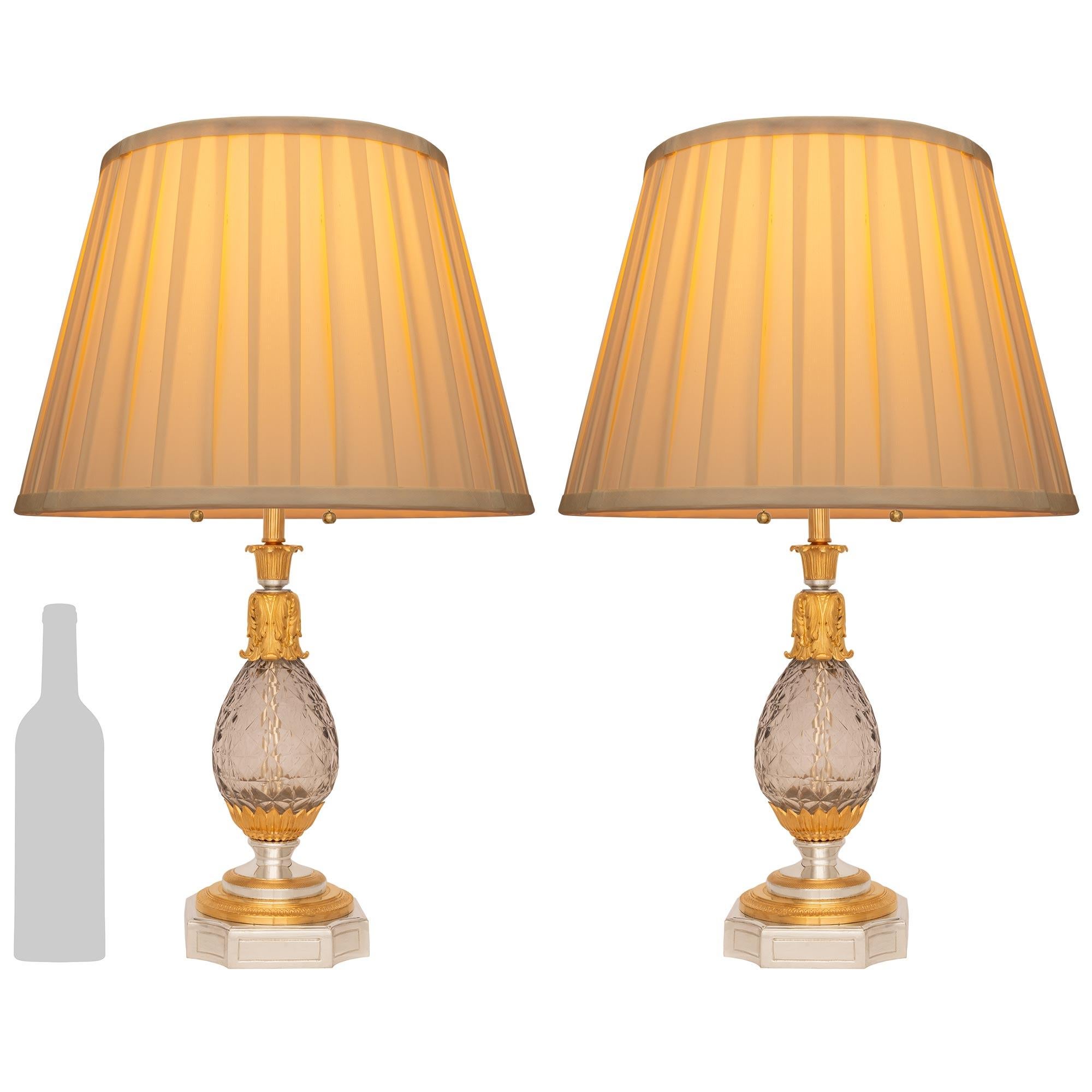 Elegante pareja de lámparas francesas del siglo XIX de cristal de Baccarat de estilo Luis XVI, bronce plateado y ormolu. Cada lámpara se eleva sobre una base de Bronce Plateado con un diseño rebajado y esquinas cóncavas. En el pedestal del zócalo