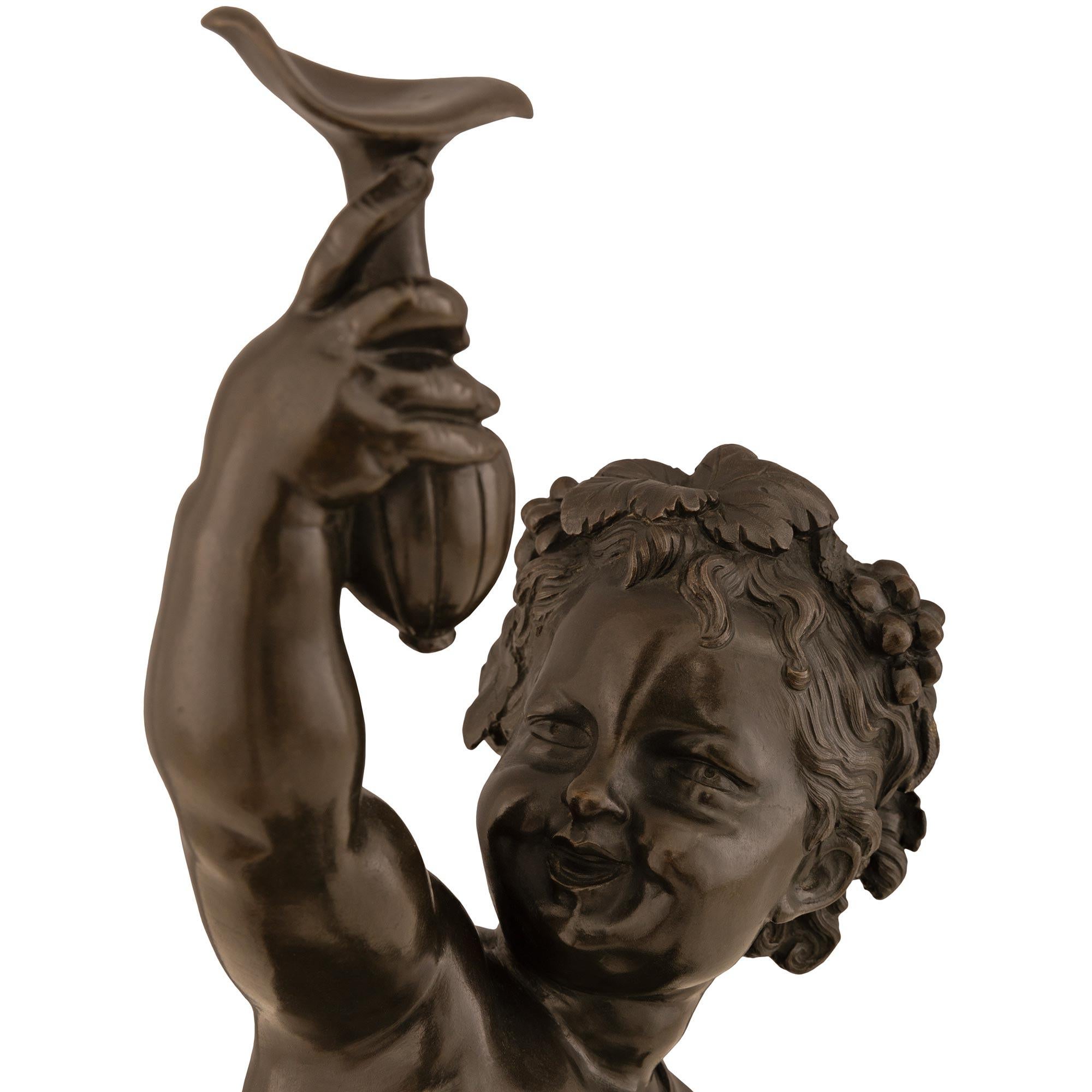 A most charming and true pair of French 19th century Louis XVI st. patinated Bronze and Vert Patricia marble statues of cherubs. Each statue is raised by a circular base with a mottled bottom border and a circular central column showcasing the