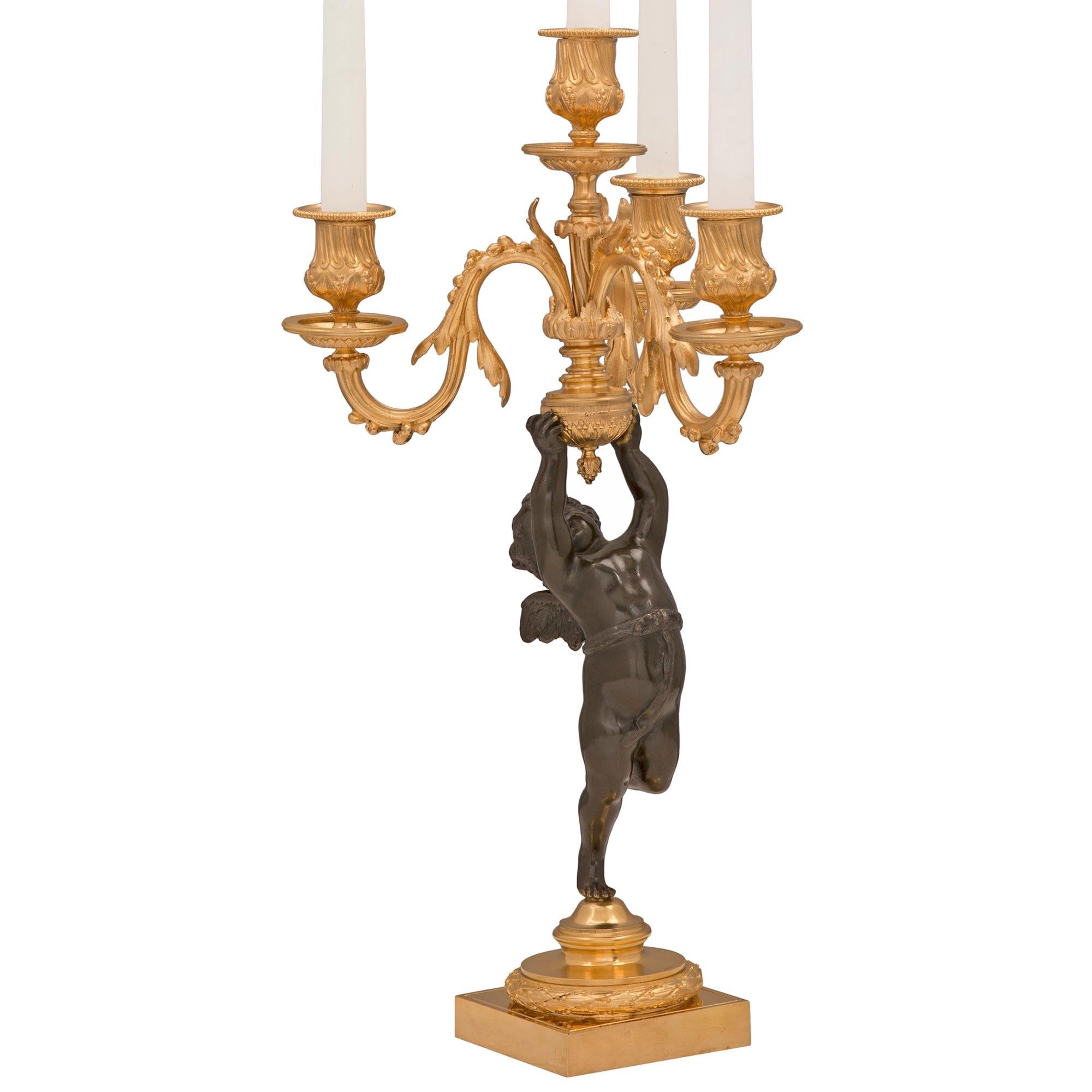 Charmante paire de candélabres français du XIXe siècle, de style Louis XVI, en bronze patiné et bronze doré. Chaque candélabre à quatre bras est surélevé par une base carrée en bronze doré avec une fine enveloppe de laurier et un support tacheté où