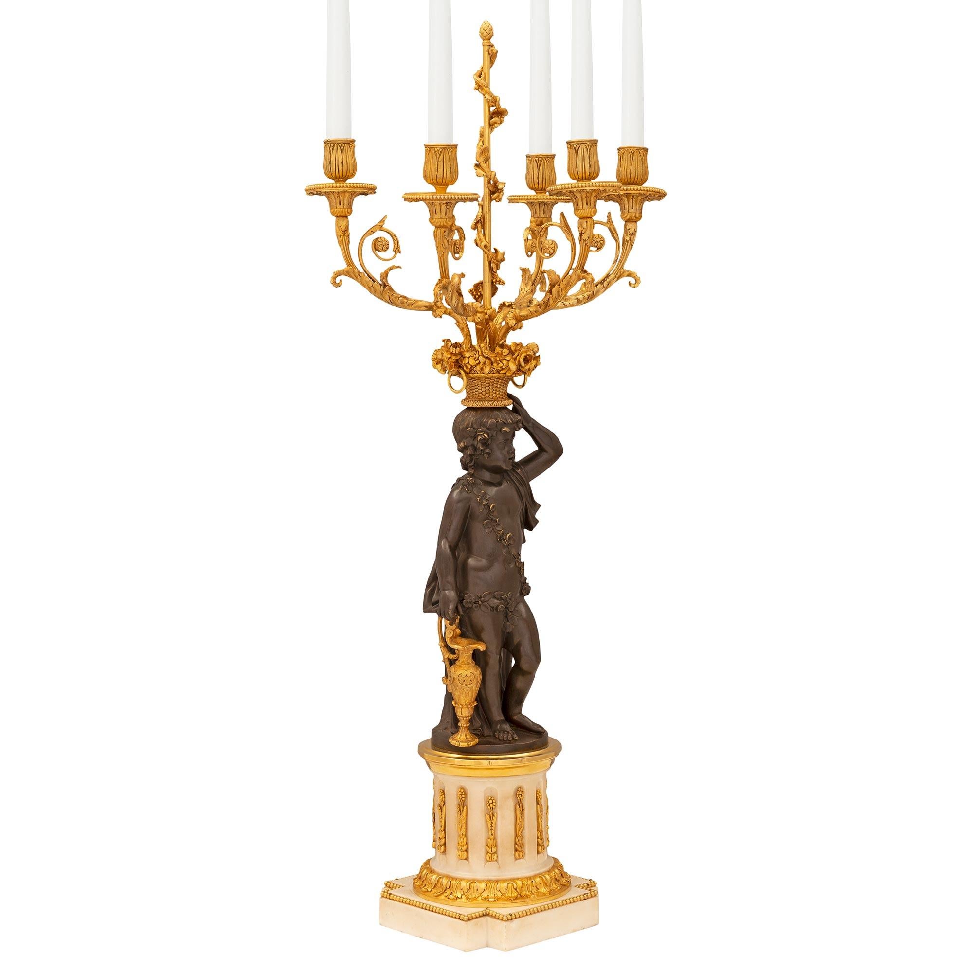 An exceptional and very high quality pair of French early 19th century Louis XVI st. patinated bronze, ormolu, and white Carrara marble candelabras circa 1805. Each five arm candelabra is raised by a square white Carrara marble base with cut corners