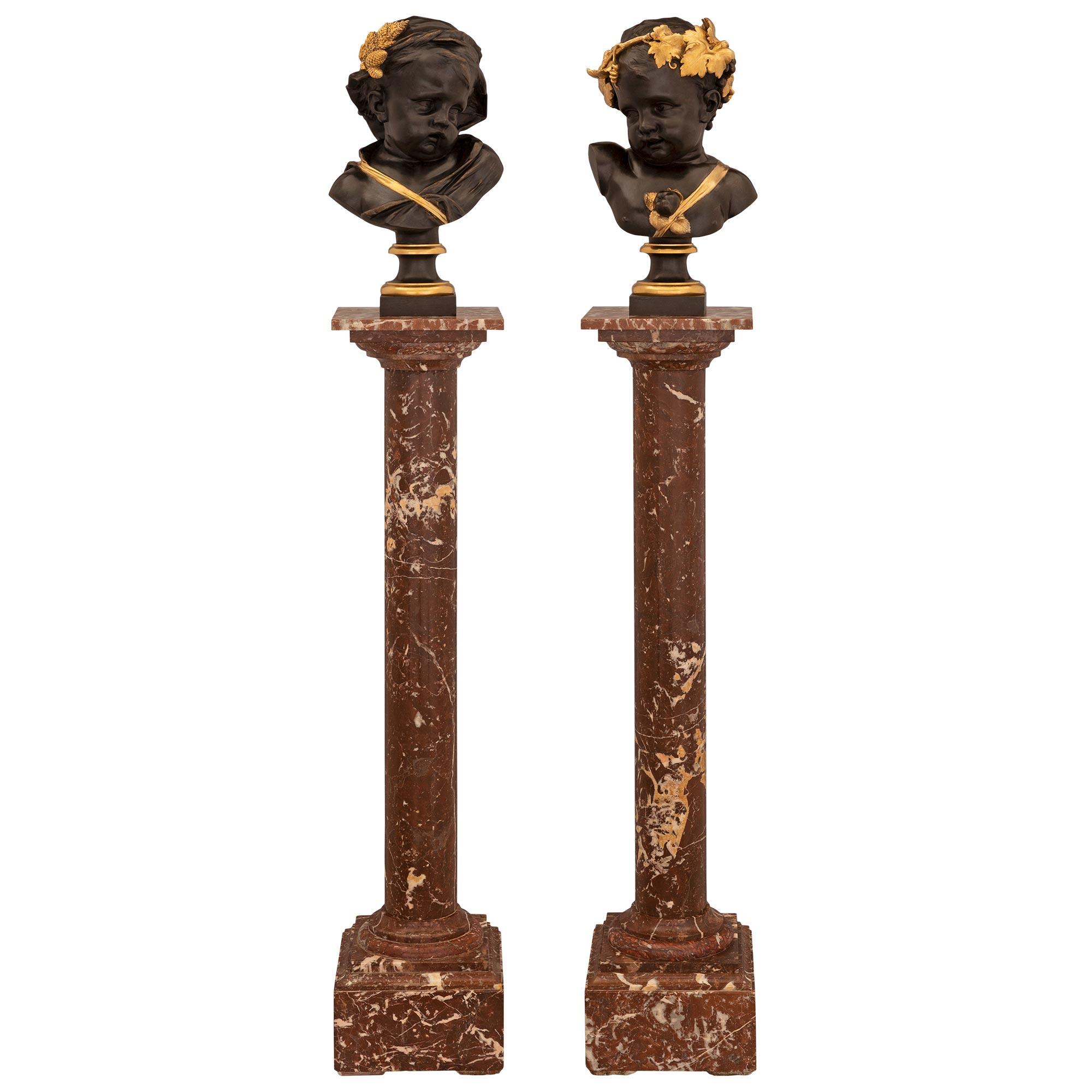 A striking and most elegant pair of French 19th century Louis XVI st. patinated bronze and ormolu cherub bust on their original Coquiller de Bilbao marble pedestal columns. Each column is raised by a square base with a fine mottled border and a