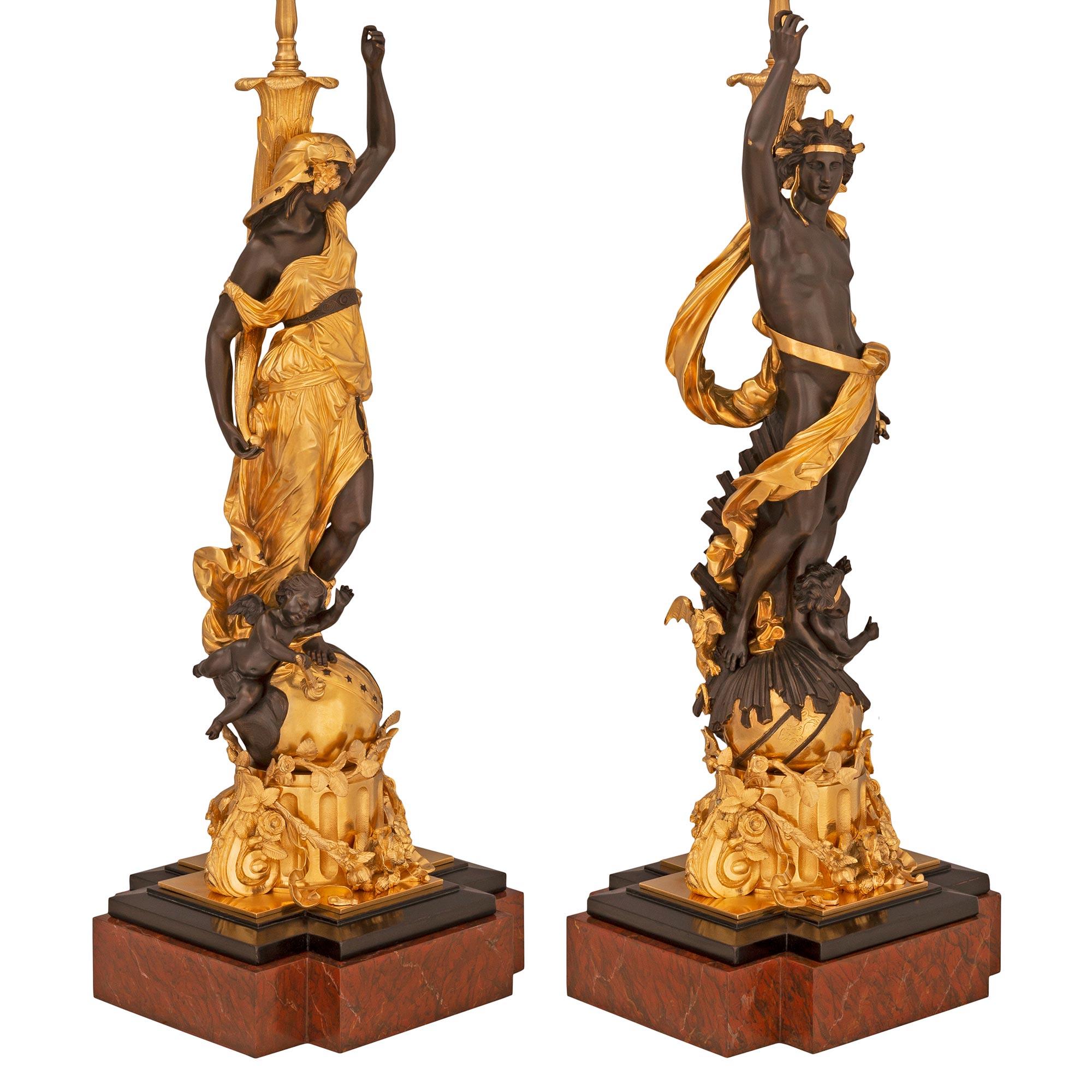 A stunning and extremely decorative true pair of French 19th century Louis XVI st. ormolu, patinated bronze, Rouge Griotte, and black Belgian marble lamps. Each lamp is raised by a handsome Rouge Griotte marble base with cut corners and a fine