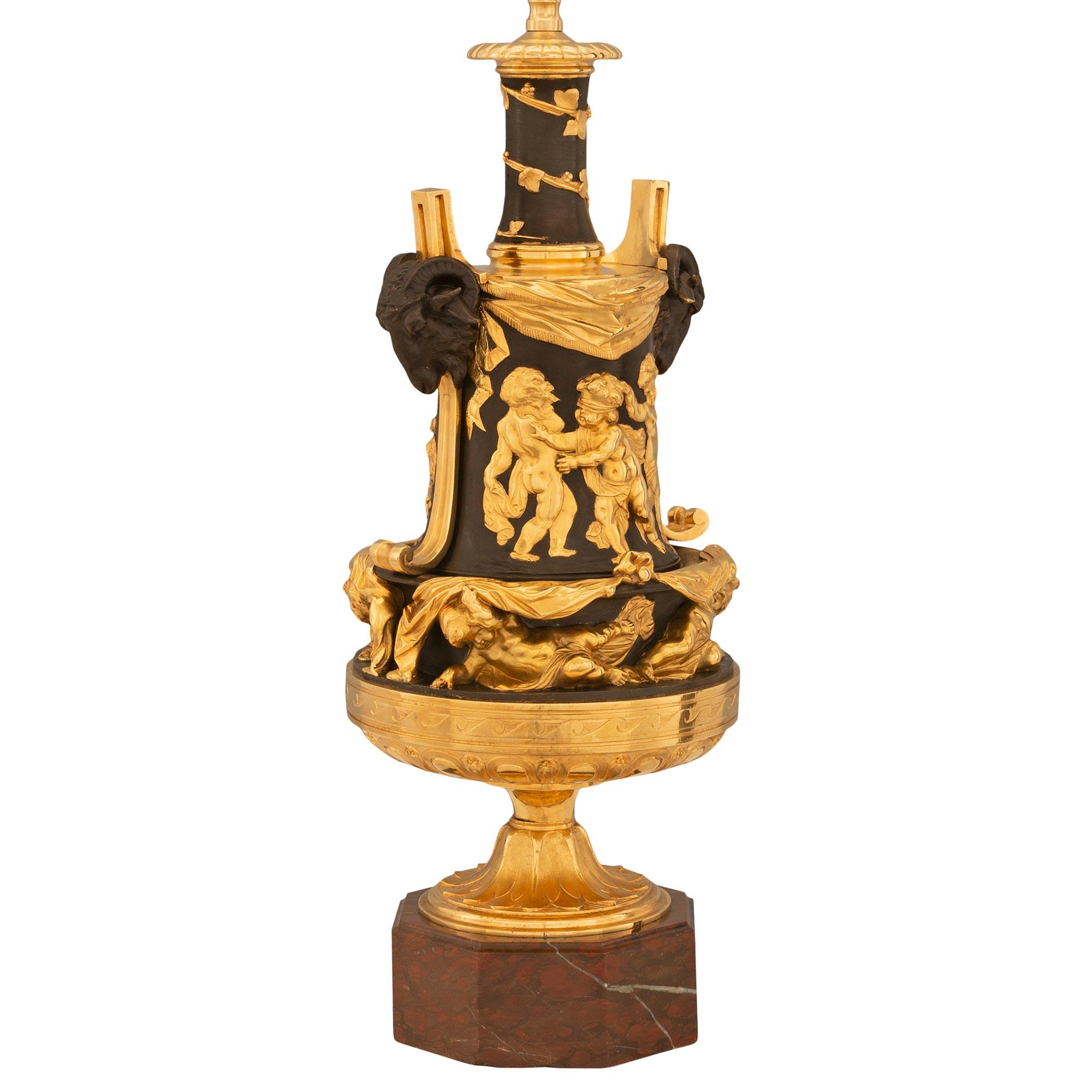 Magnifique et unique paire de lampes en bronze doré, bronze patiné et marbre Rouge Griotte de style Louis XVI du XIXe siècle. Chaque lampe est surmontée d'une remarquable base octogonale en marbre Rouge Griotte, avec une fine bordure tachetée et un