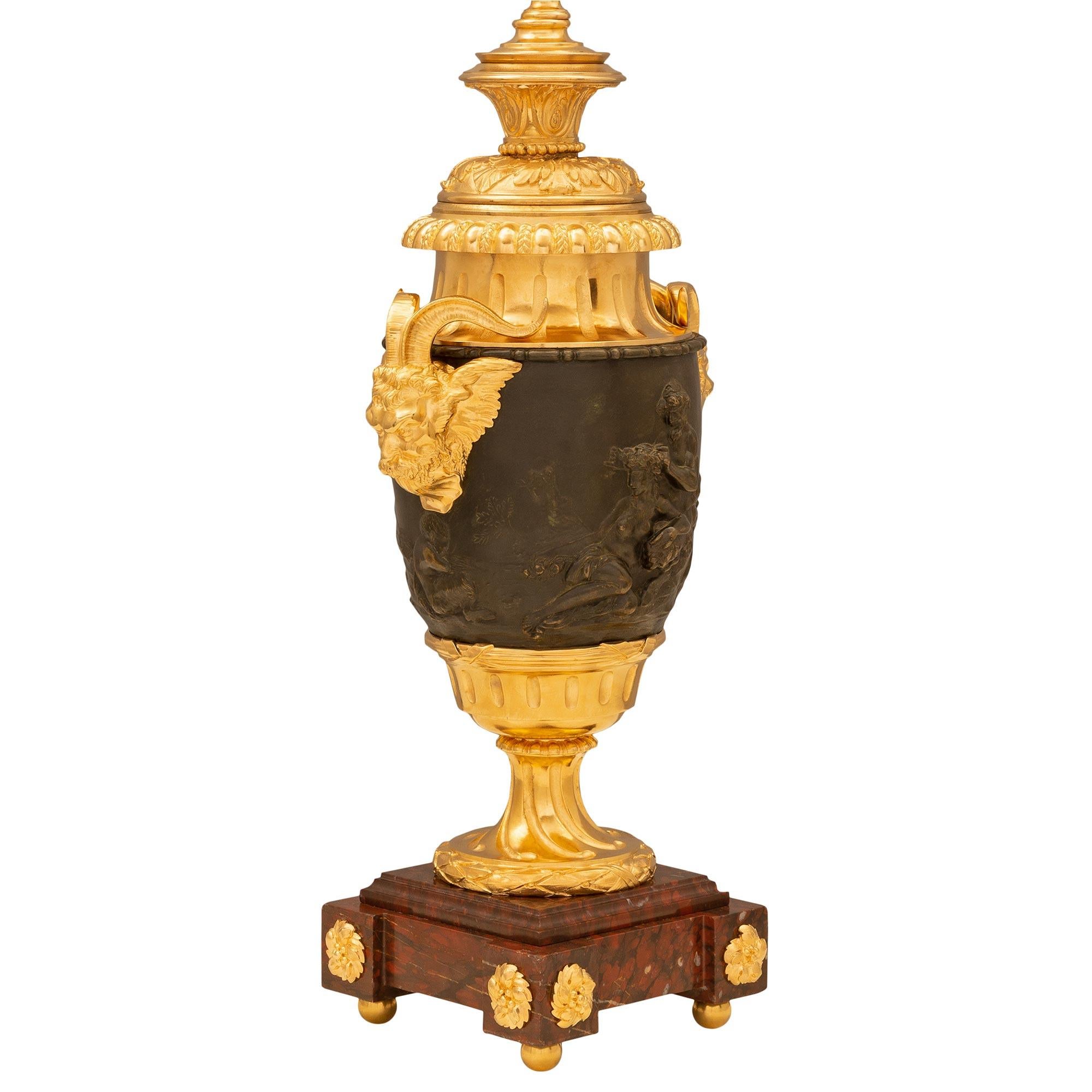 Paire impressionnante de lampes en bronze patiné, bronze doré et marbre Rouge Griotte, de style Louis XVI, datant du 19ème siècle et réalisées à la manière de Clodion. Chaque lampe est surélevée par une base carrée en marbre Rouge Griotte avec des