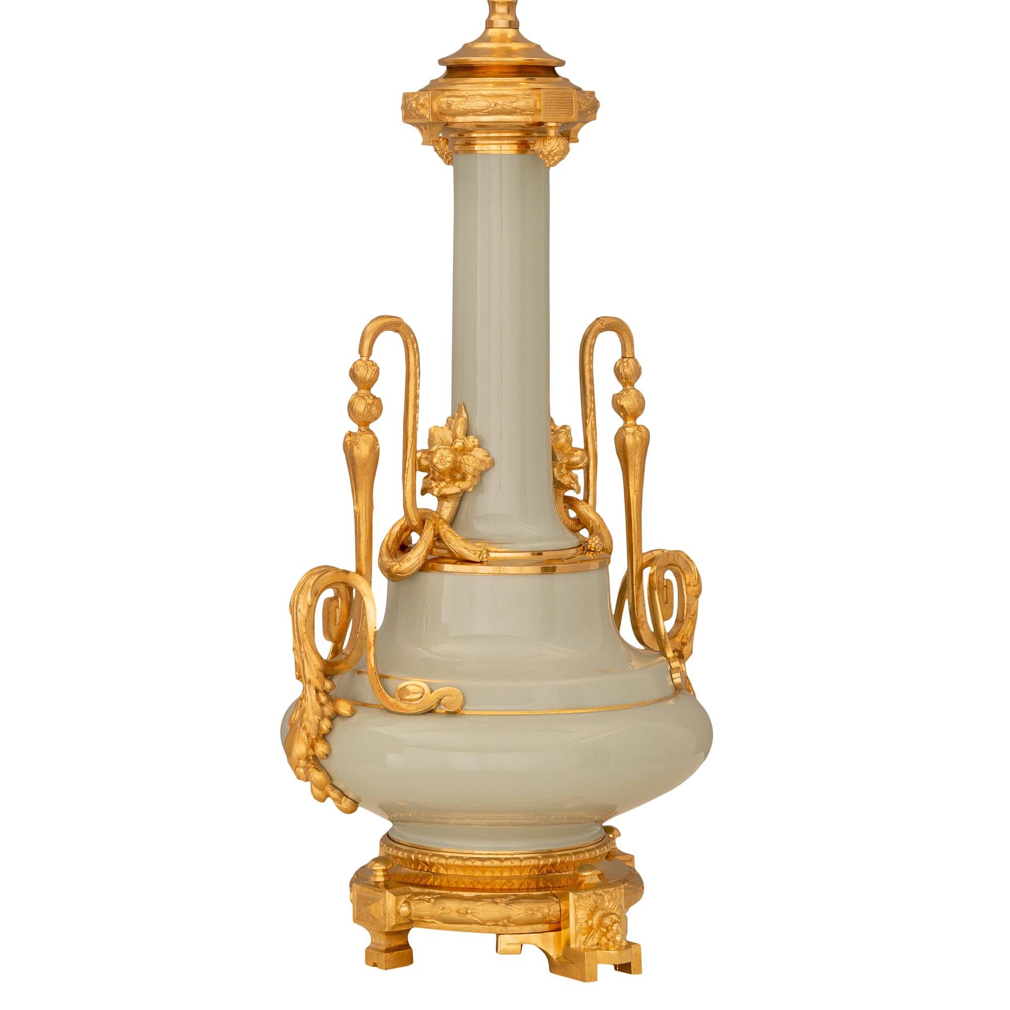 A beautiful pair of French 19th century Louis XVI st. celadon porcelain and ormolu lamps. Each lamp is raised by an elegant circular ormolu base with fine rosette block feet and wrap around berried laurel and Coeur de Rai designed bands. The
