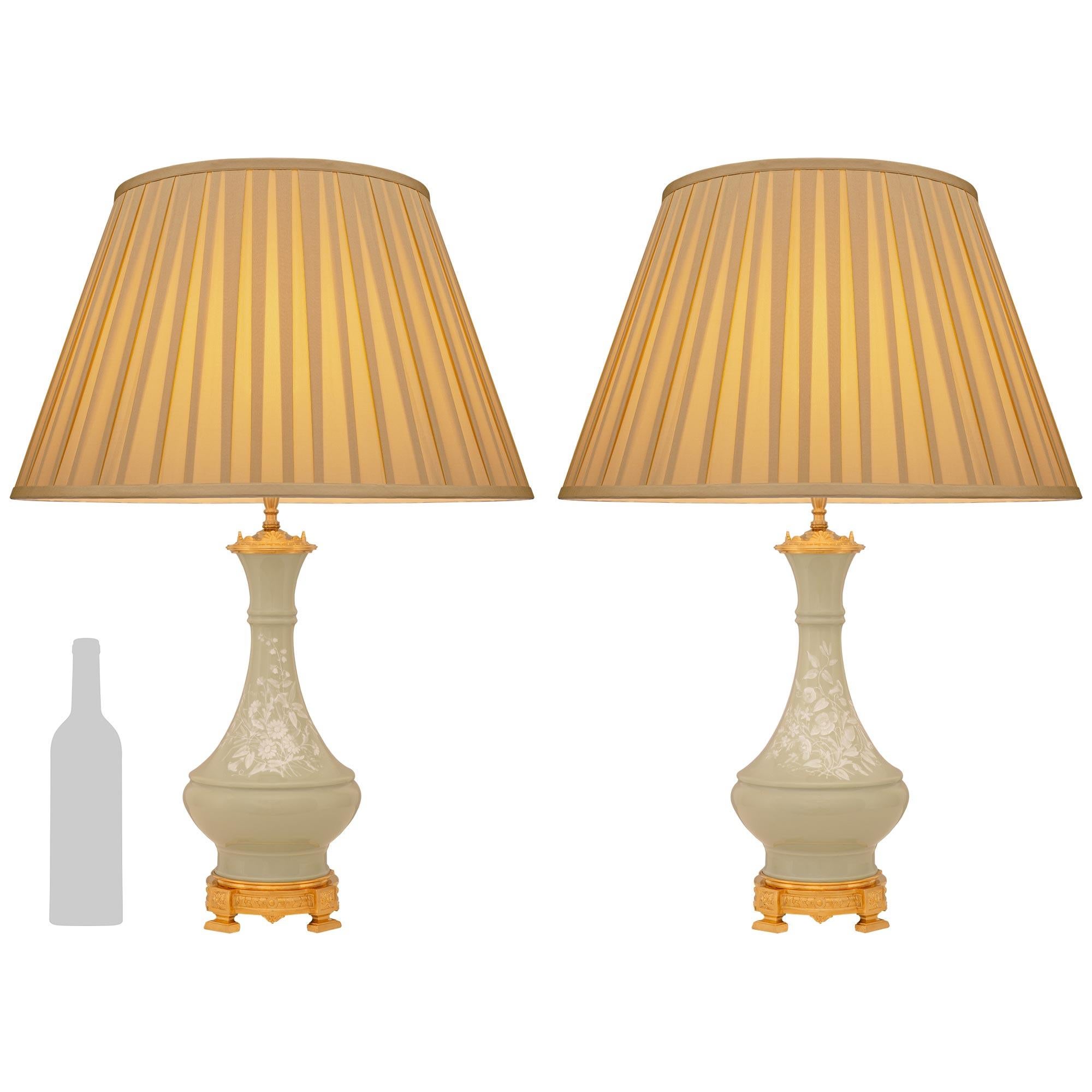 Paire de lampes élégantes et très décoratives en porcelaine céladon et bronze doré de style Louis XVI du XIXe siècle, attribuées à Limoges. Chaque lampe à deux lumières Pâte sur Pâte est surmontée d'une base mouchetée décorée de feuillages en bronze