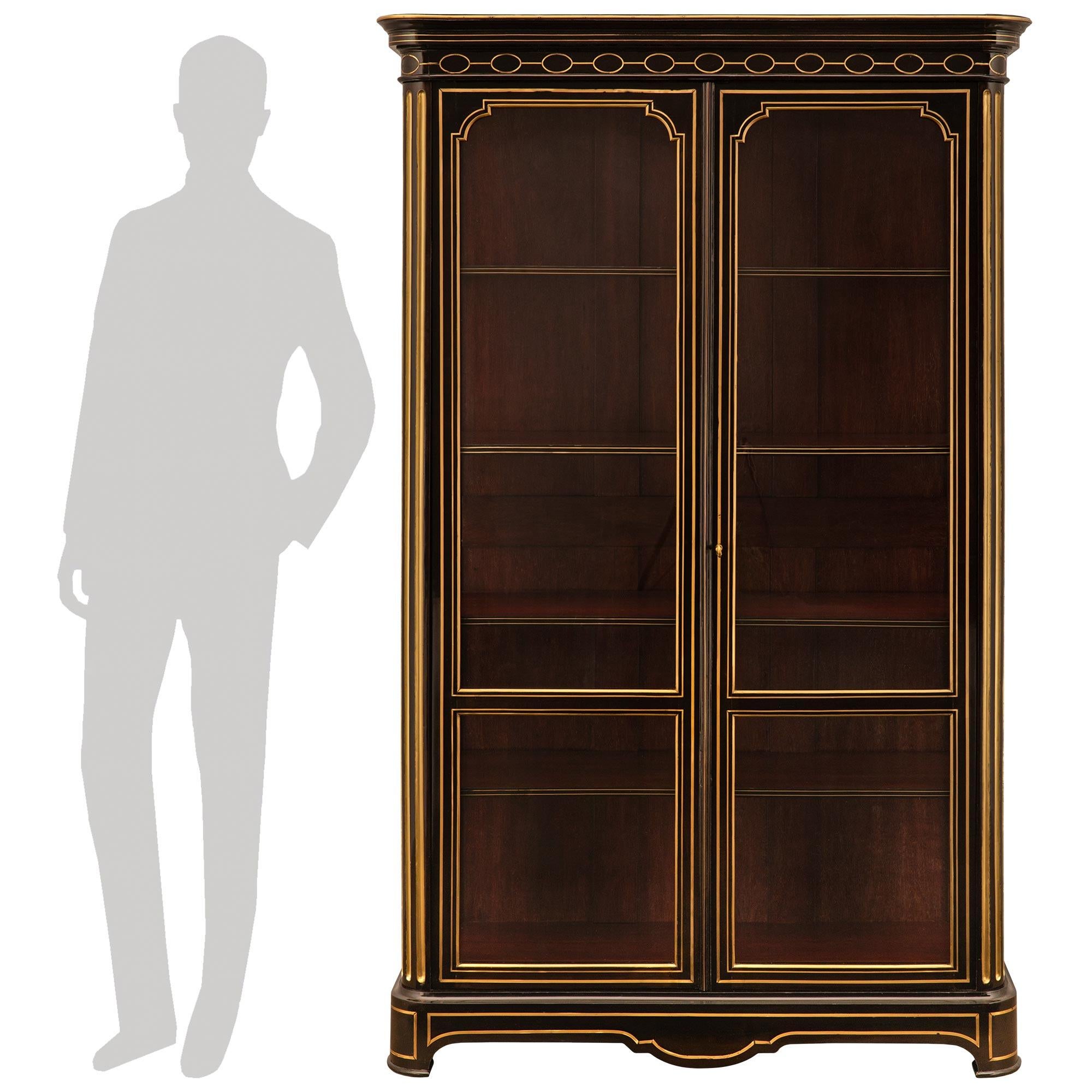 Una coppia impressionante e di alta qualità di vetrine Boulle in ebano e legno dorato del XIX secolo. Ogni splendida vetrina intarsiata in ottone è sollevata da quattro gambe corte con un grembiule a forma di arbusto e finiture in legno dorato. Gli