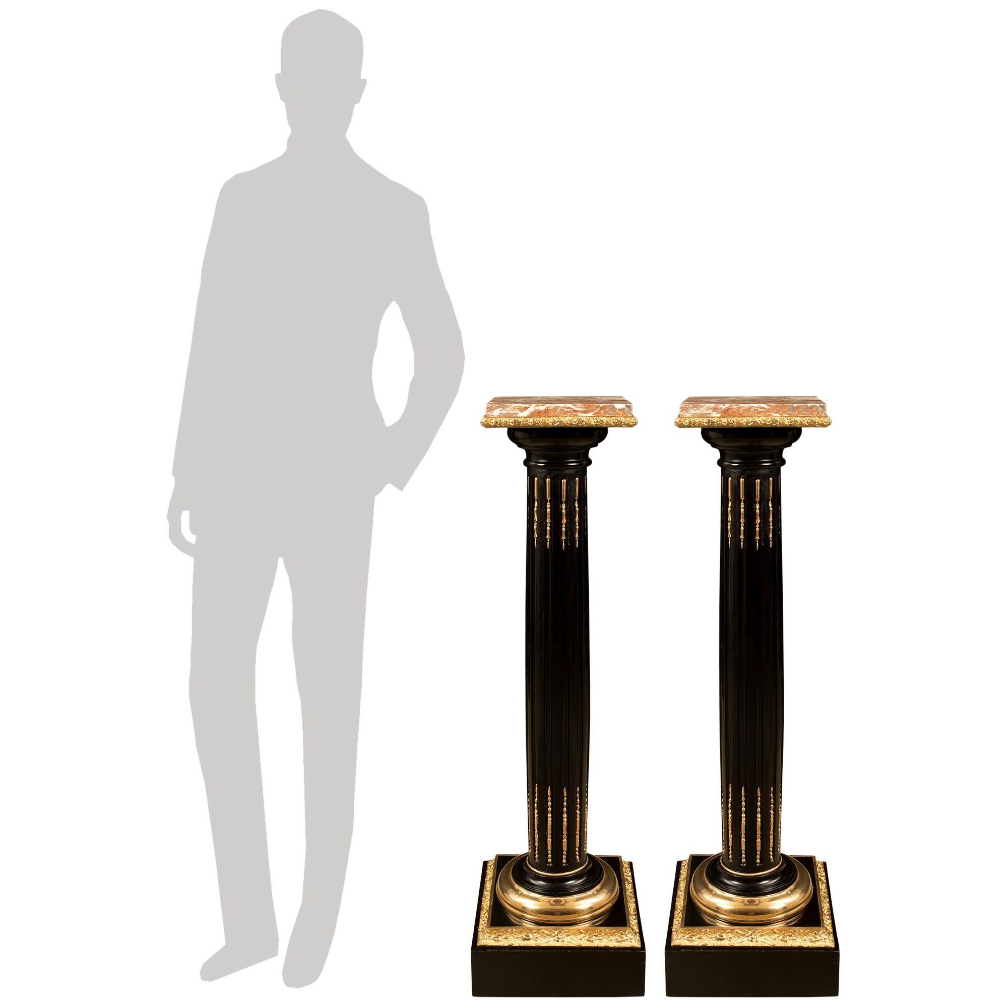 An impressive and extremely elegant pair of French 19th century Louis XVI st. Ebony, Ormolu and Marble pedestals. Each stunning pedestal is raised by a square Ebony base with a fine wrap around foliate Ormolu band. The central Ebony supports display