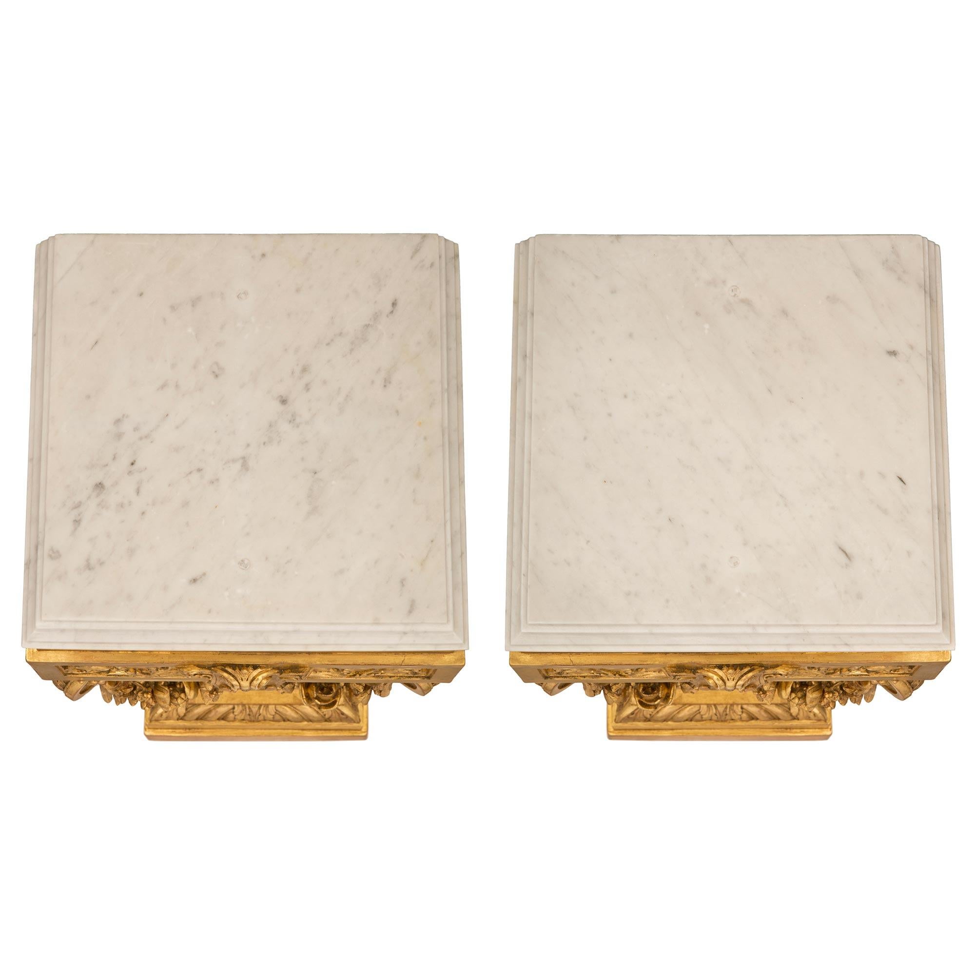 An impressive and high quality pair of French 19th century Louis XVI st. Napoleon III period giltwood and white Carrara marble pedestal columns. Each pedestal is raised by a square base with a stepped design and a most decorative gadroon design with