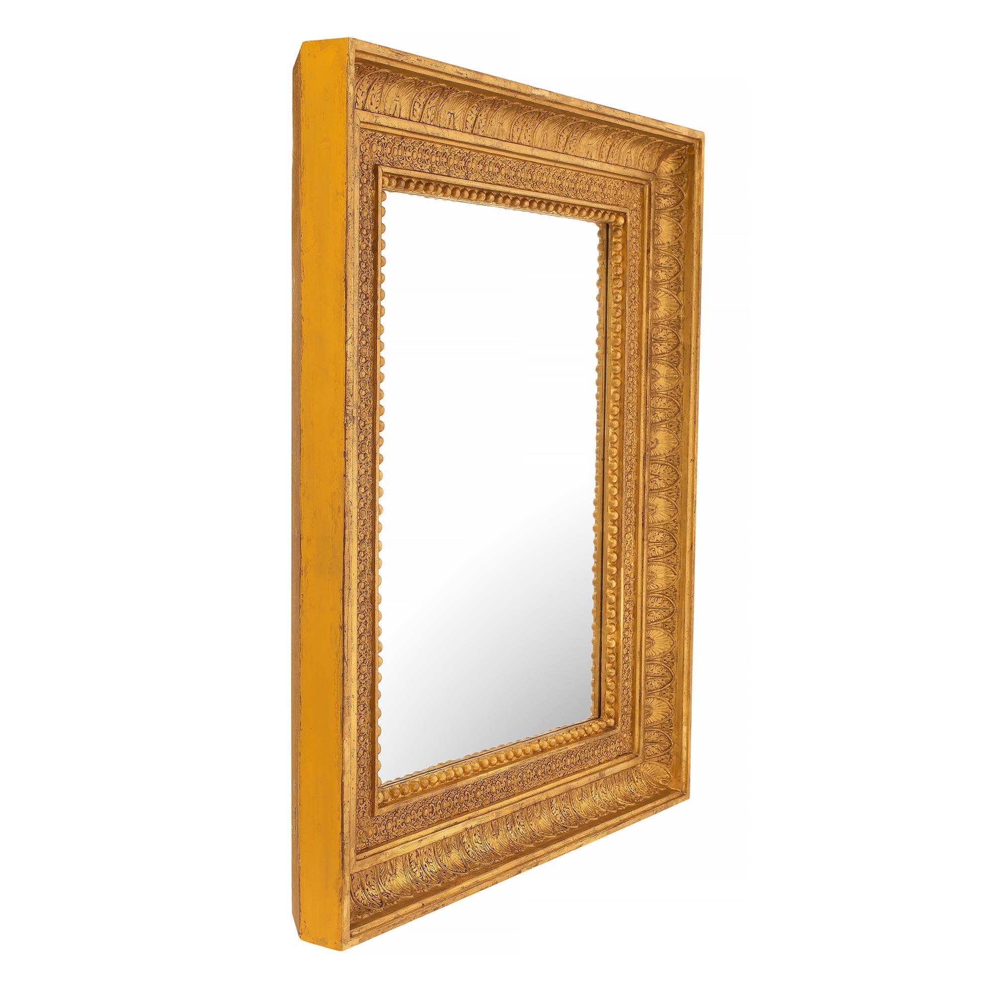 Une belle paire de miroirs en bois doré de style Louis XVI du 19ème siècle. Chaque miroir conserve sa plaque d'origine, encadrée d'une bordure en bois doré chiné richement sculptée. La bordure présente un fin motif perlé et de belles sculptures de