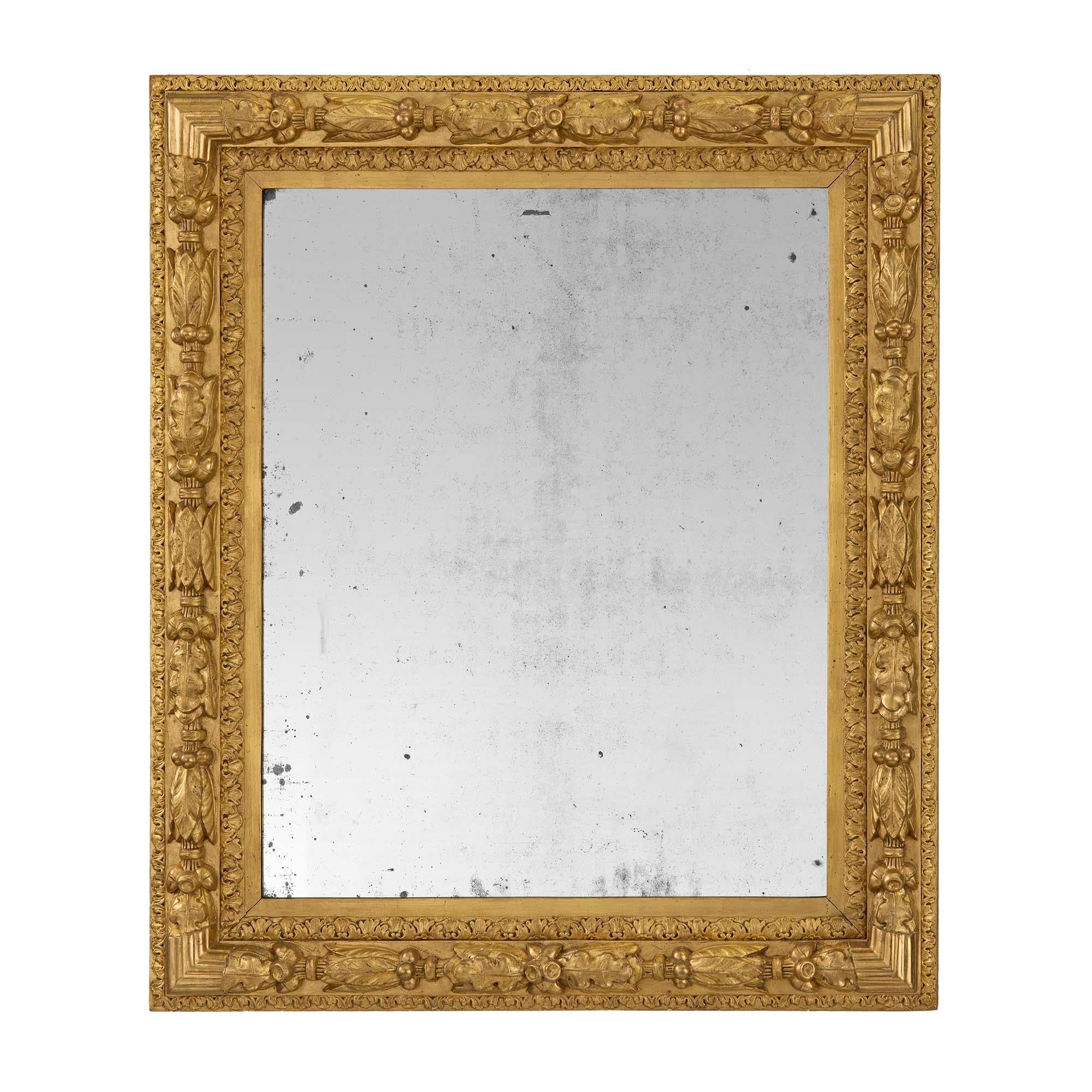 Paire de miroirs en bois doré de style Louis XVI du XIXe siècle. Chaque miroir a conservé sa plaque d'origine encadrée par de magnifiques bordures en bois doré moucheté. Le cadre présente une bande feuillagée richement sculptée, des feuilles de