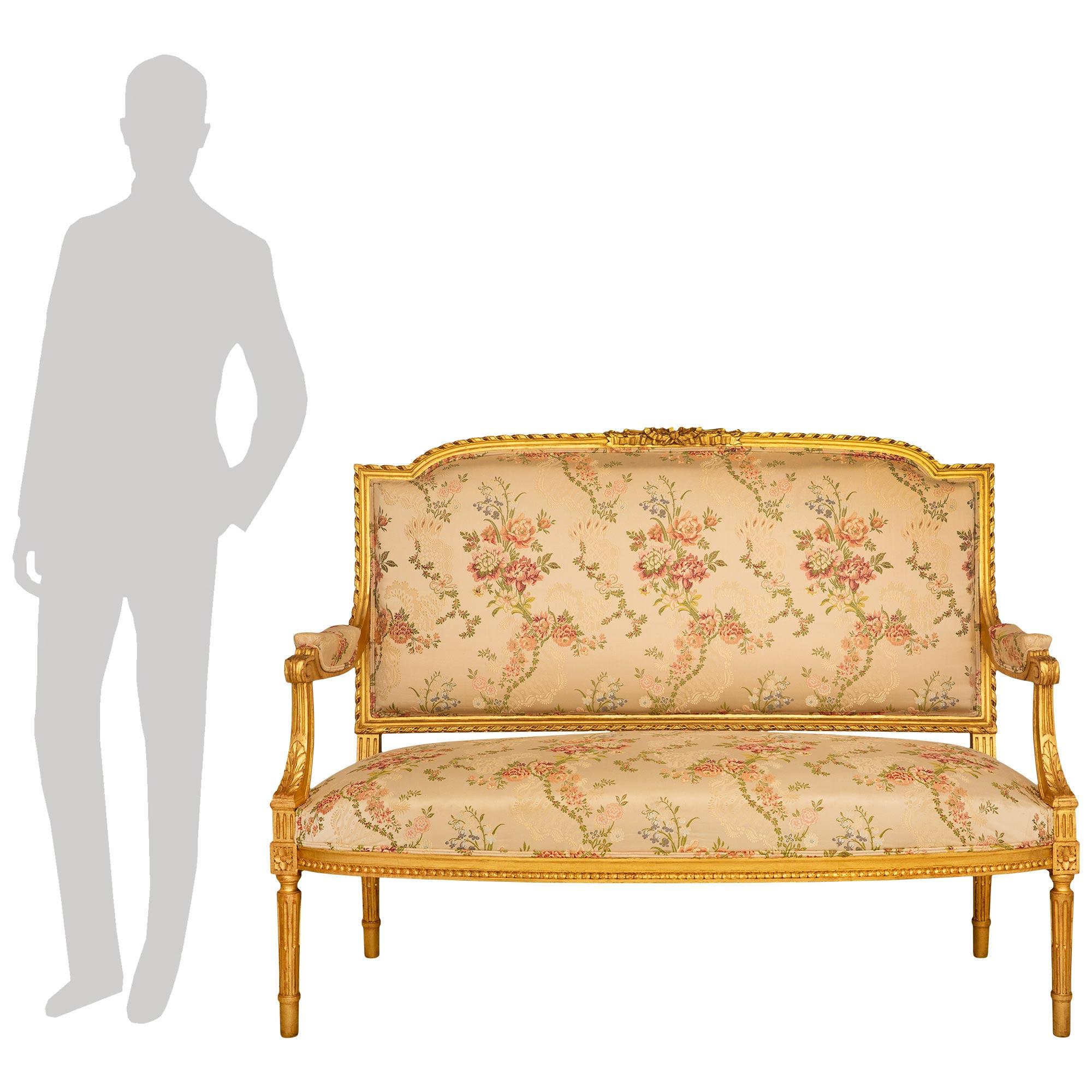 Une paire décorative et très élégante de canapés en bois doré de style Louis XVI du 19ème siècle. Chaque magnifique canapé repose sur quatre pieds droits fuselés et cannelés, avec des blocs de couronnement à rosette finement sculptés. Les blocs de