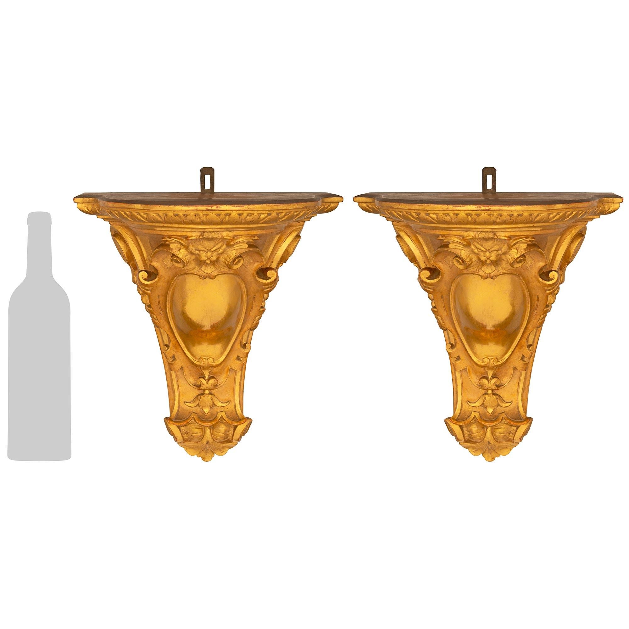 Ein hübsches und sehr charmantes Paar französischer Wandkonsolen aus Giltwood im Stil Louis XVI des 19. Jede wunderbare Wandhalterung zeigt ein zentrales verziertes Cabochon-Wappen mit einer maskulinen, skurrilen Maske oben. Die Konsolen verjüngen