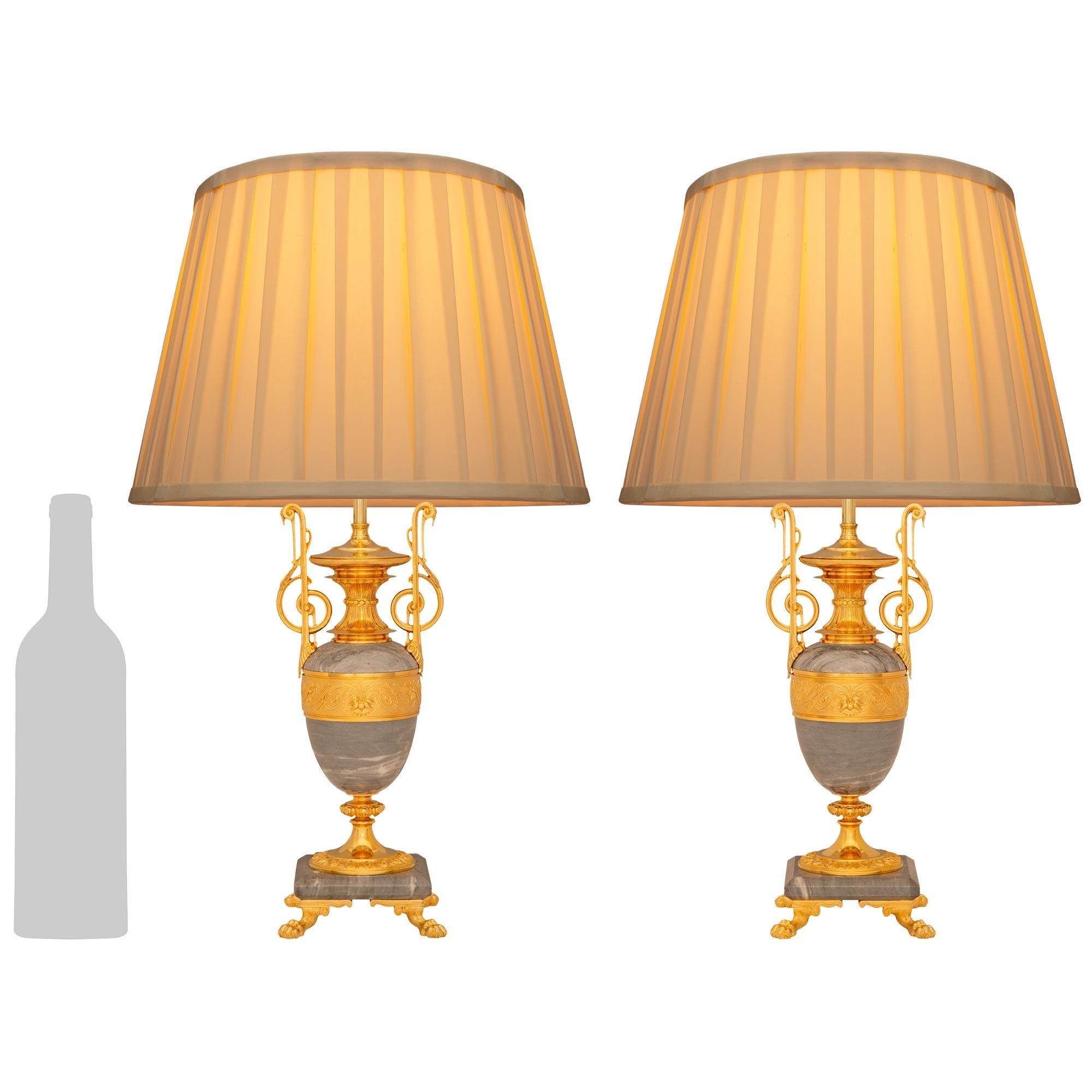 A beautiful and most elegant pair of French 19th century Louis XVI st. Gris St. Anne marble and Ormolu lamps. Each stunning lamp is raised on a mottled square marble plate while being supported on Ormolu pawed feet in each corner. Above the marble