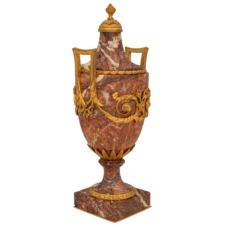 A most elegant pair of French 19th century Louis XVI st. Sarrancolin marble and ormolu urns, signed E. KAHN. Each urn is raised by a square marble base with a fine bottom ormolu fillet and an elegant wrap around berried laurel band at the socle