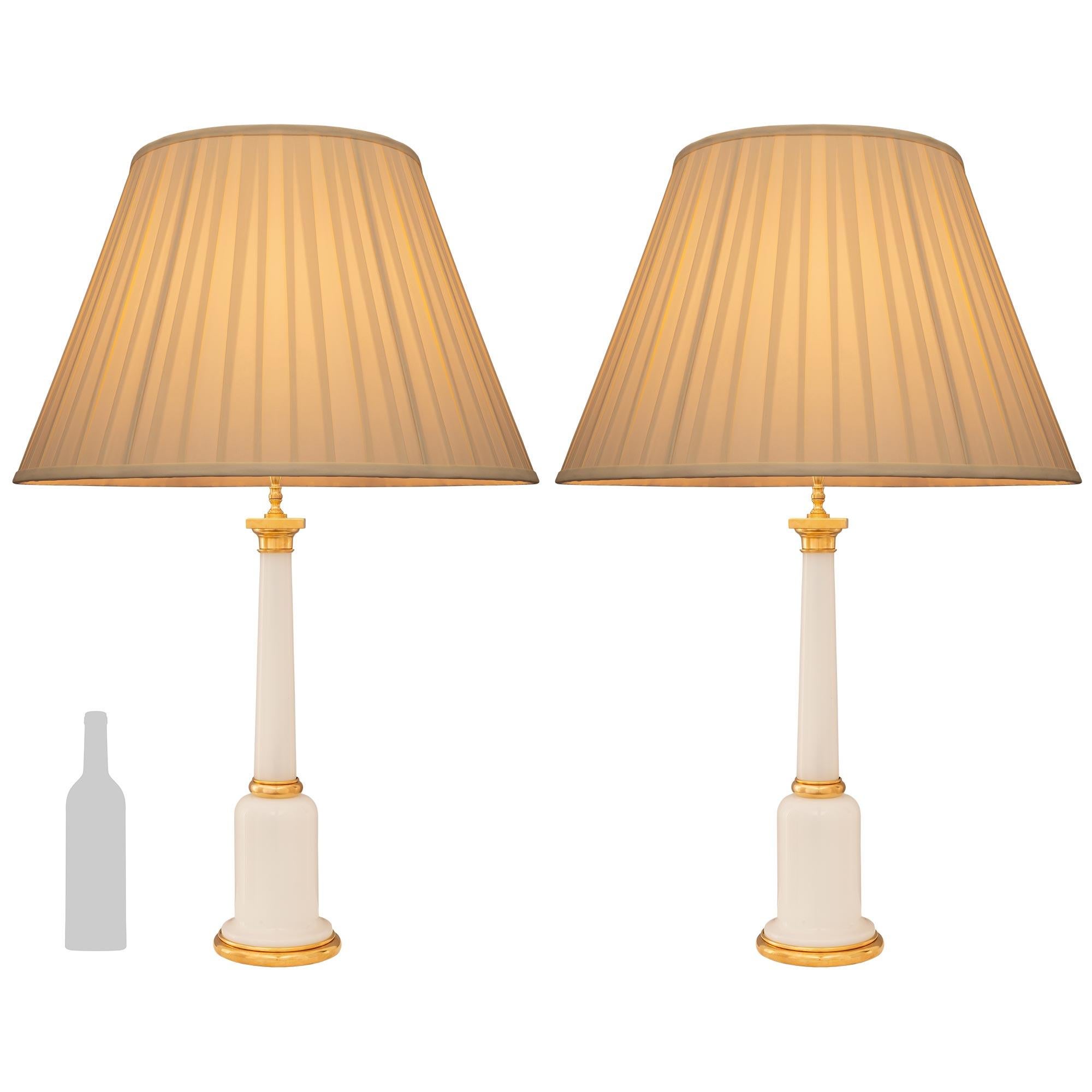 A beautiful and most elegant pair of French 19th century Louis XVI st. Opaline Glass and Ormolu lamps. Each lamp is raised by a fine circular Ormolu base below the beautifully shaped Opaline support with a lovely smooth and curvaceous design. Above