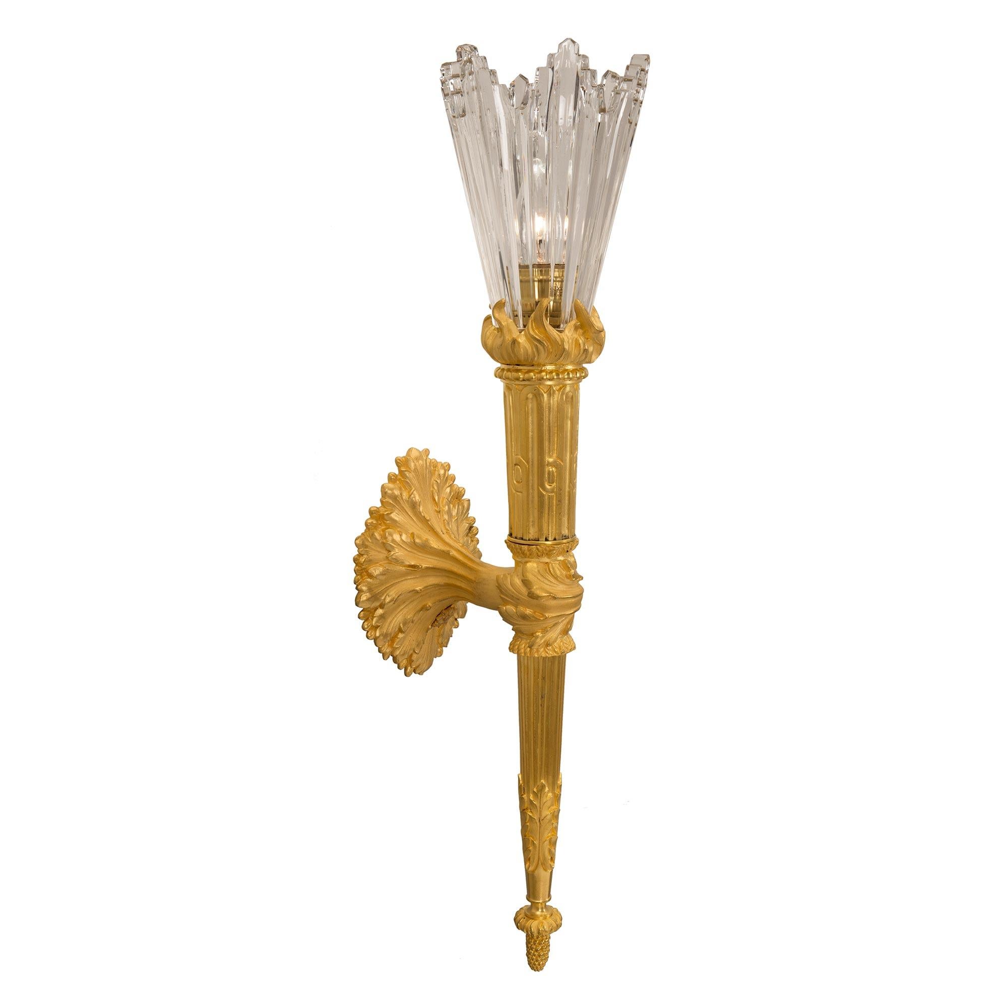 An exceptional and most unique true pair of French 19th century Louis XVI st. ormolu and Baccarat crystal sconces. Each sconce is centered by a fine inverted bottom acorn finial below the elegant tapered fluted central support. The support displays