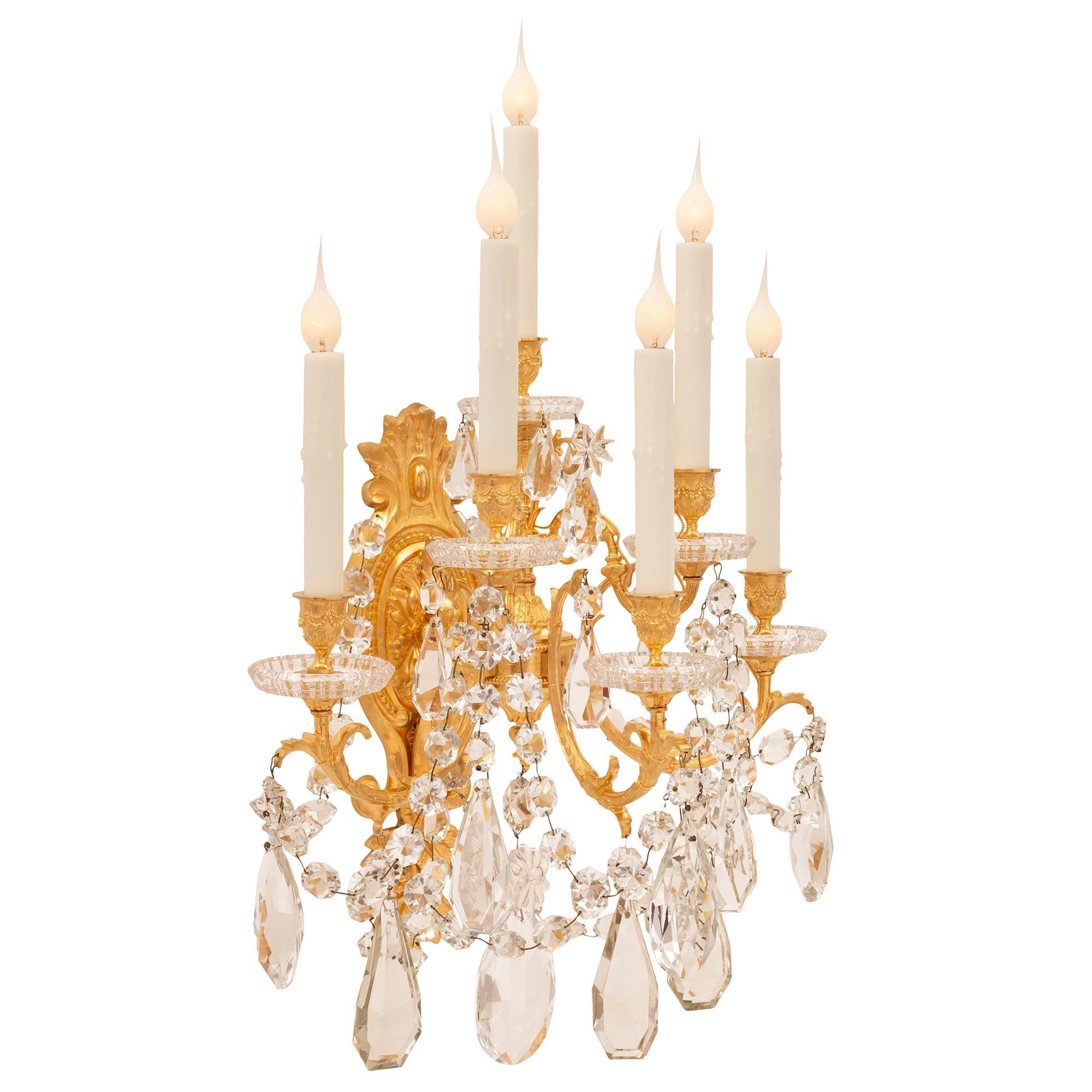 An exceptional pair of French 19th century Louis XVI st. ormolu and Baccarat crystal sconces. Each six arm sconce is centered by a superb ormolu backplate with elegant foliate designs from where the arms branch out. The elegantly curved arms spread