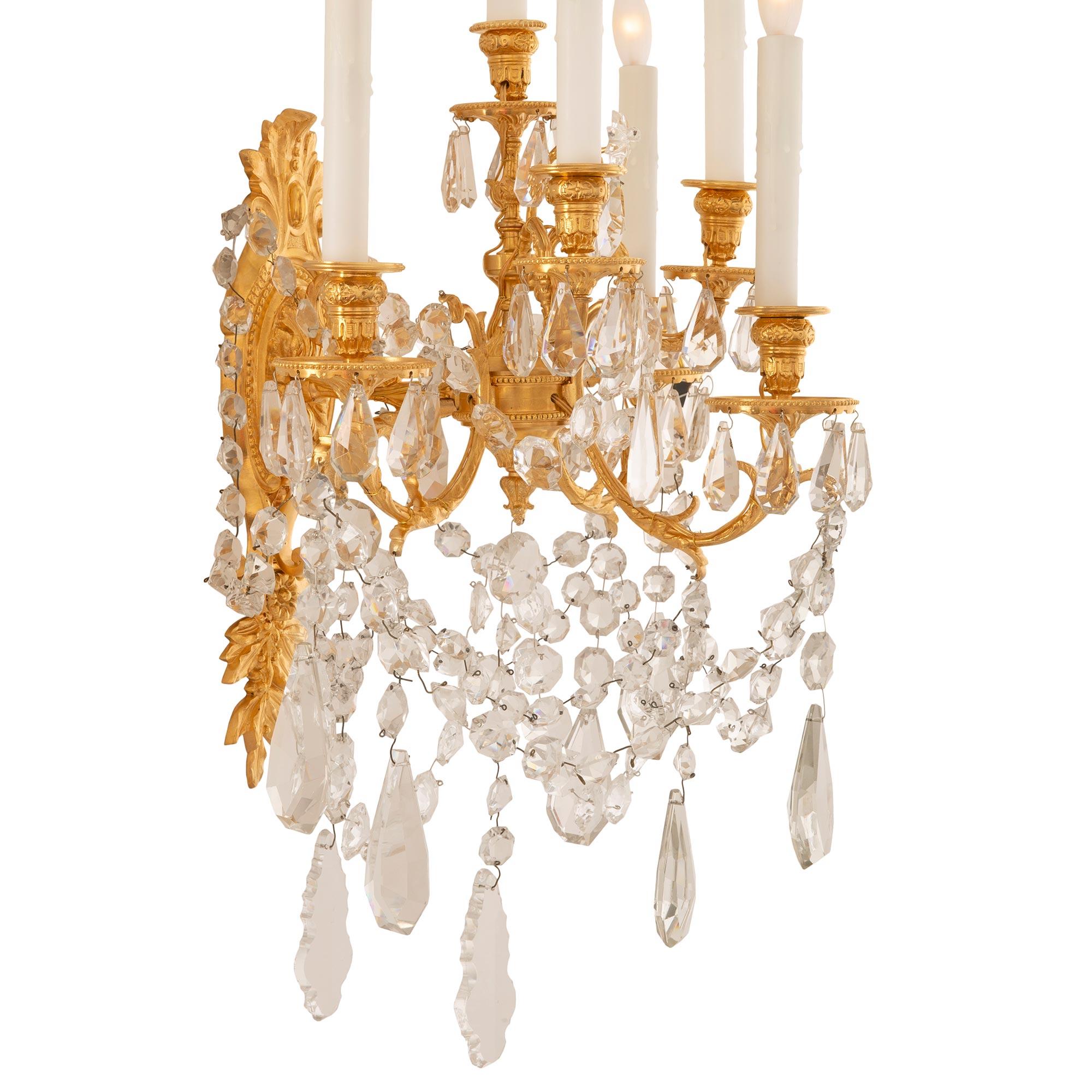 A stunning and most impressive pair of French 19th century Louis XVI st. ormolu and Baccarat crystal sconces. Each six arm sconce is centered by an exceptional and most decorative array of cut Baccarat crystal pendants amidst beautiful swaging