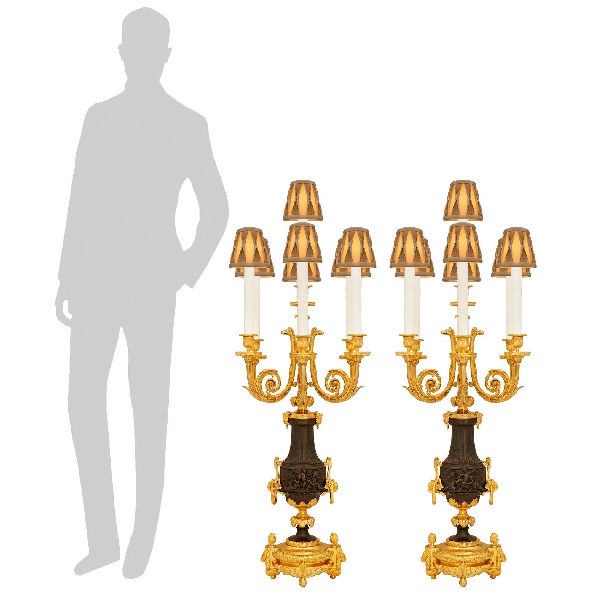 Una coppia impressionante e di alta qualità di lampade a candelabro francesi del XIX secolo in stile Luigi XVI, in ormolu e bronzo patinato, alla maniera di Clodion. Ogni candelabro elettrificato più eccezionale è sollevato su una base ovale in