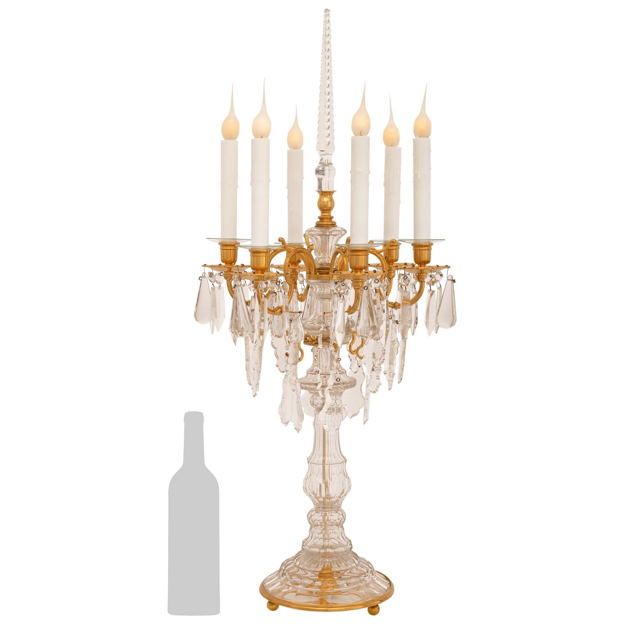 Une belle et impressionnante paire de lampes candélabres en bronze doré et cristal de style Louis XVI du 19ème siècle. Chaque candélabre électrifié à six bras est monté sur une élégante base circulaire en bronze doré et en cristal, avec de fins