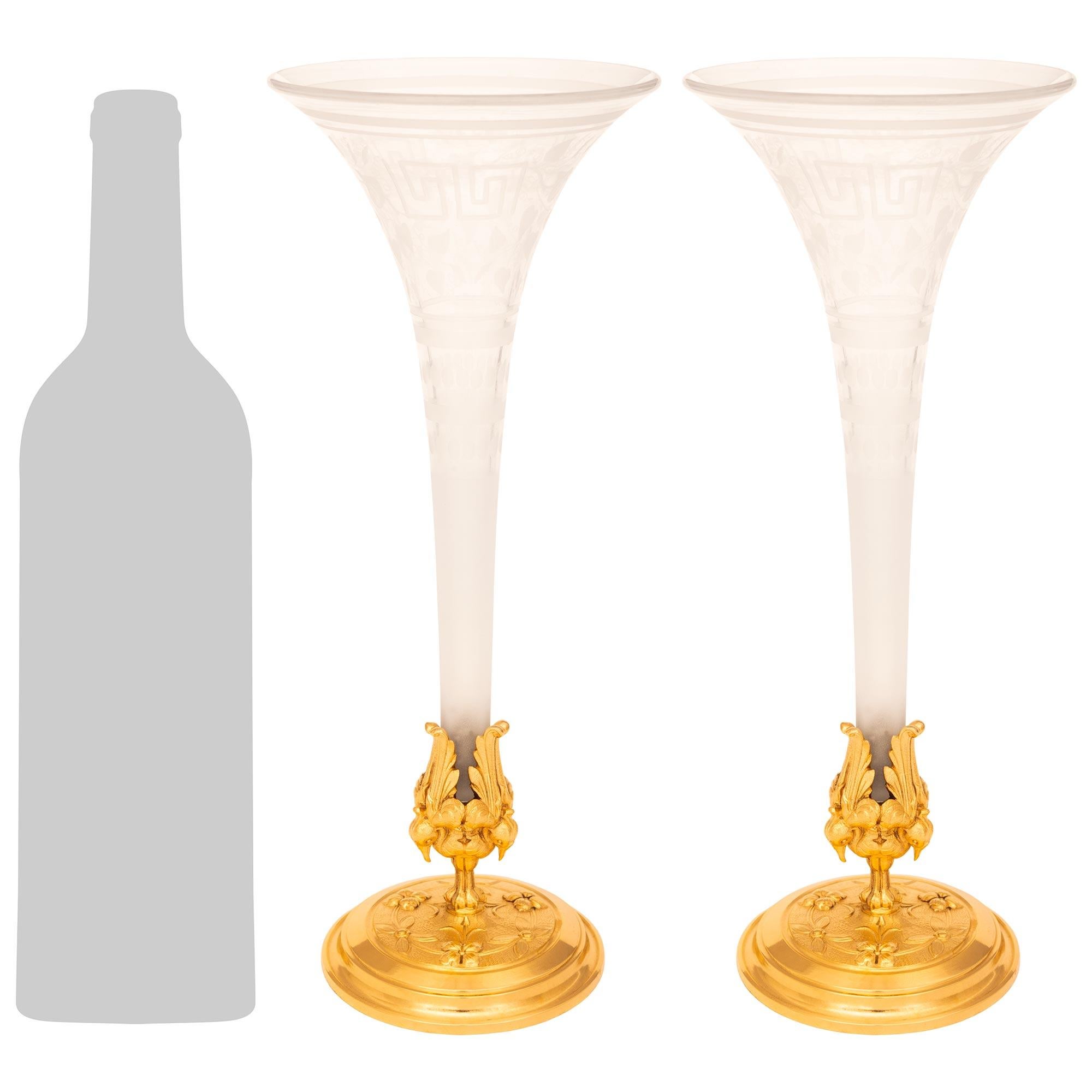 Paire de vases en bronze doré et cristal gravé de style Louis XVI du XIXe siècle, d'une grande élégance. Chaque superbe vase repose sur une base circulaire en bronze doré avec des bandes tachetées sous un fond martelé accentué par des nœuds et des